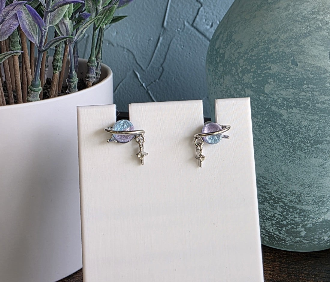 Purple and blue gemstone studs resembling planets with star dangles