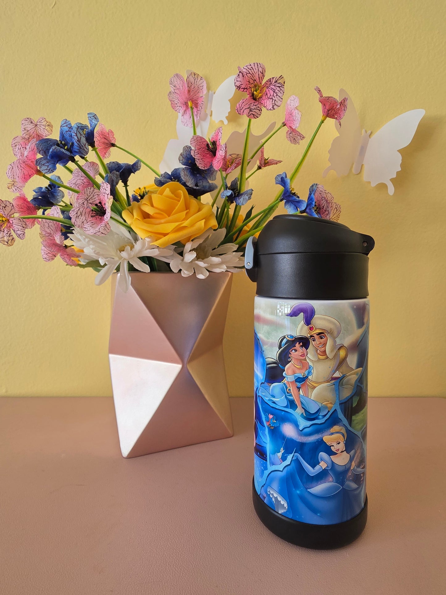 Disney character tumbler on a table with flowers in the background.