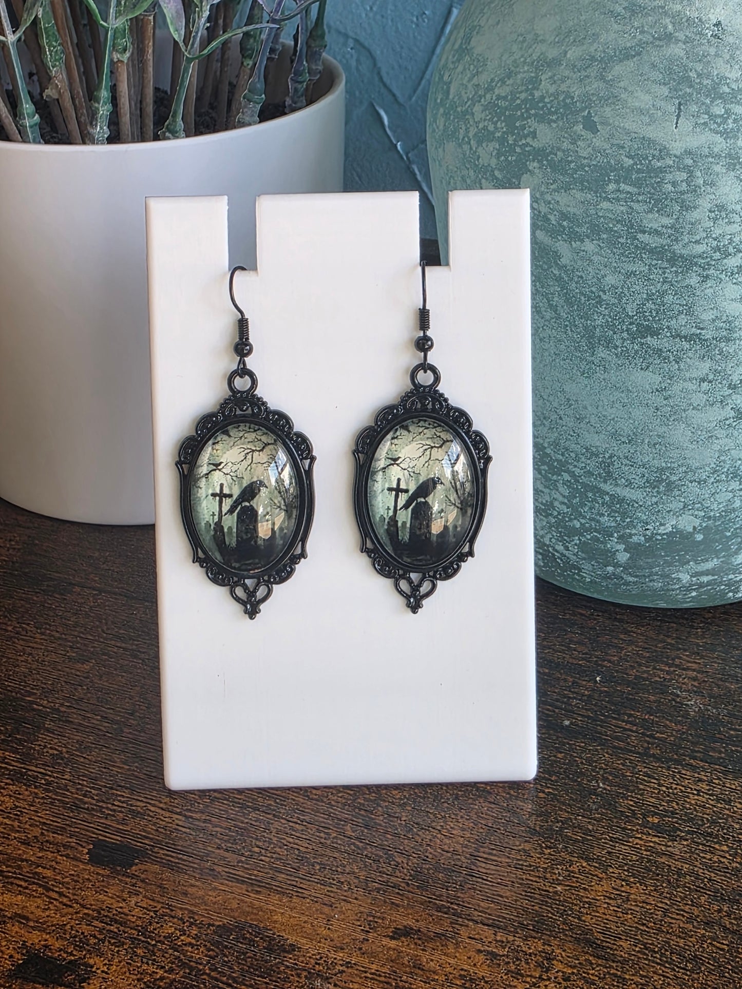 Antique style earrings with image of a crow in a grave yard.