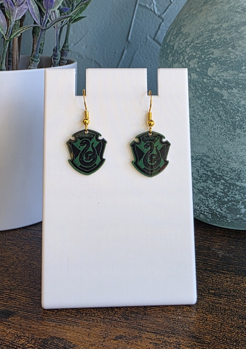 Harry Potter Slytherin House earrings with gold finishes.