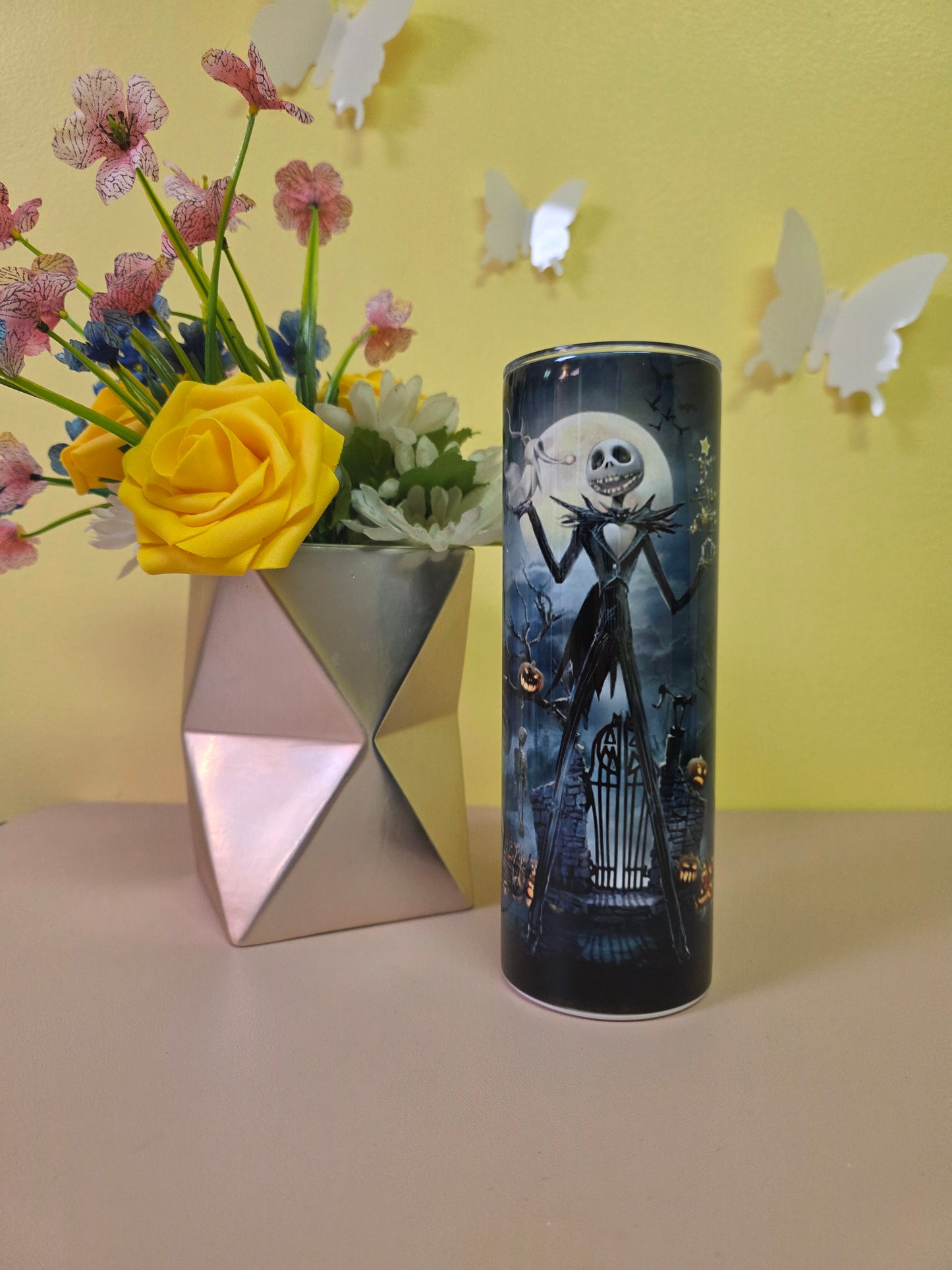 Jack Skellington Halloween Tumbler on a pink surface with yellow background.