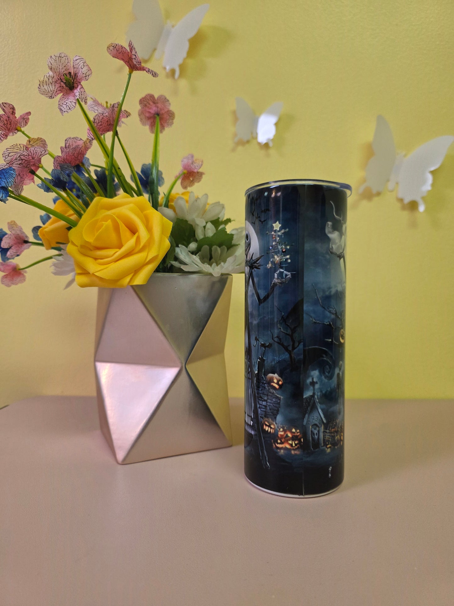 Jack Skellington Halloween Tumbler on a pink surface with yellow background.
