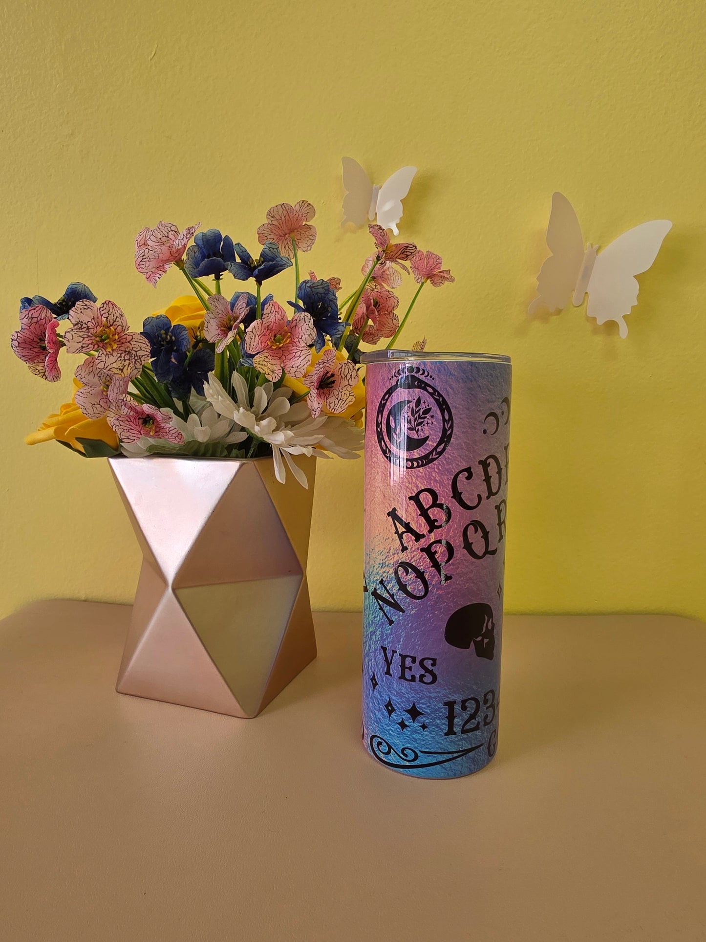 Colorful cylindrical vase with flowers on a yellow background