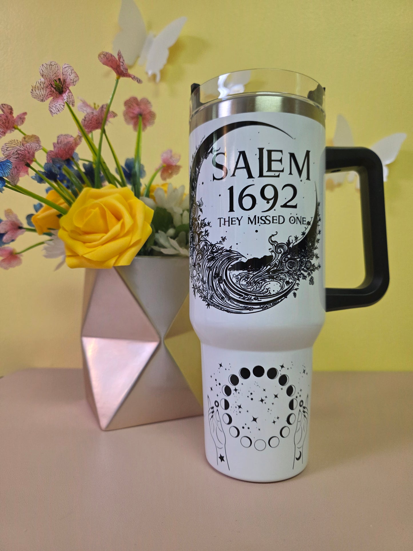 Salem Witch Trials tumbler on a pink surface with yellow background