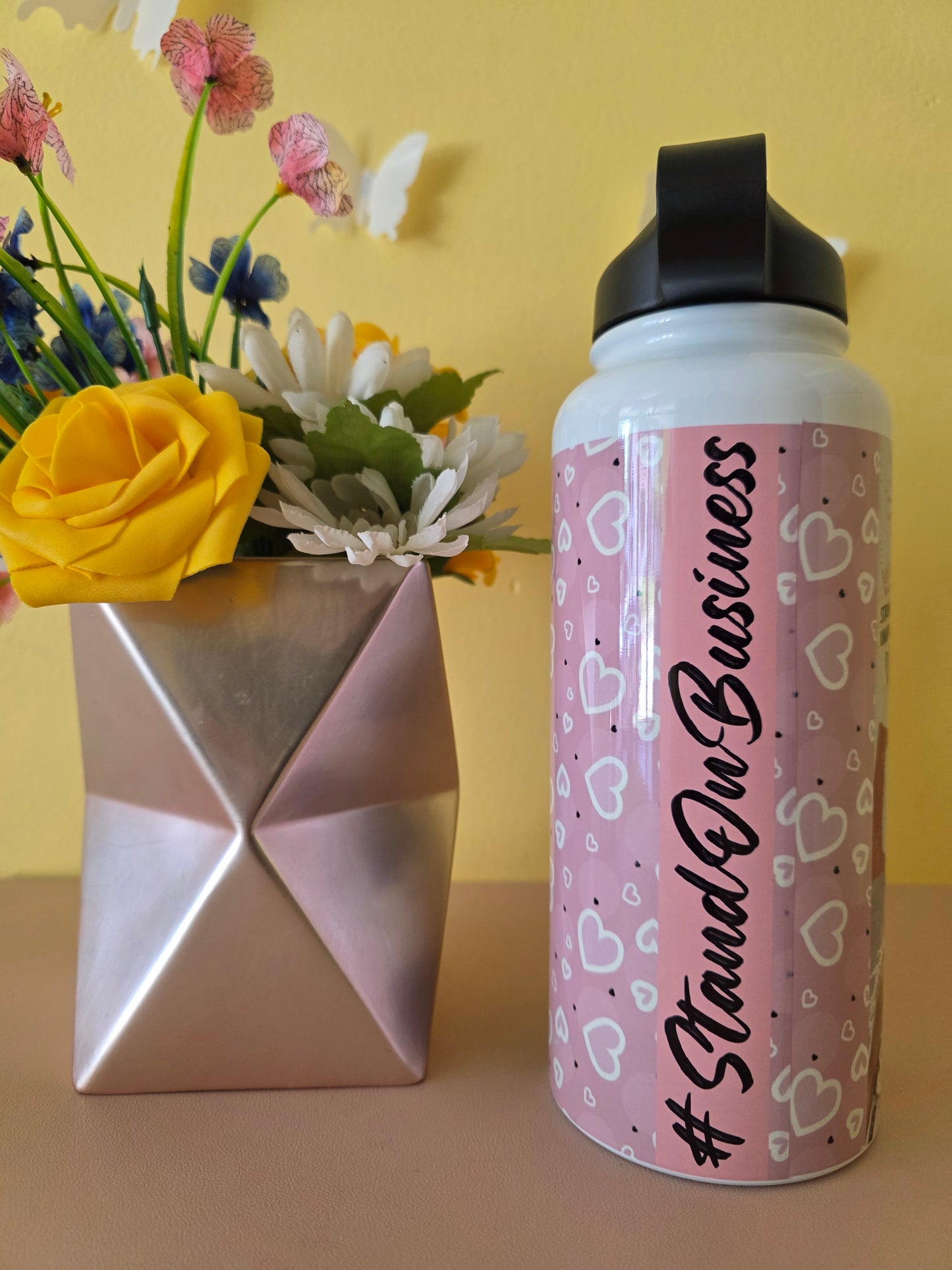 Custom women’s basketball collage water bottle with inspirational quotes displayed beside a geometric vase and yellow rose