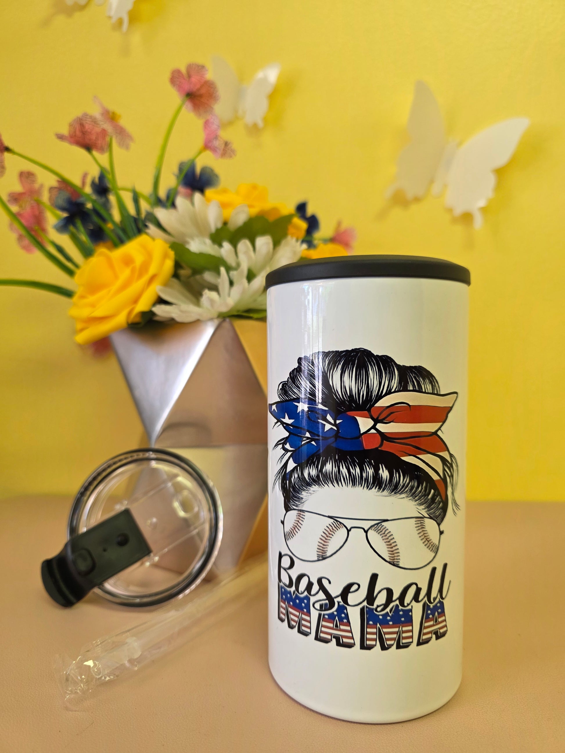 Insulated 4‑in‑1 stainless steel tumbler with baseball‑themed American flag design, shown with lid, straw, and floral arrangement