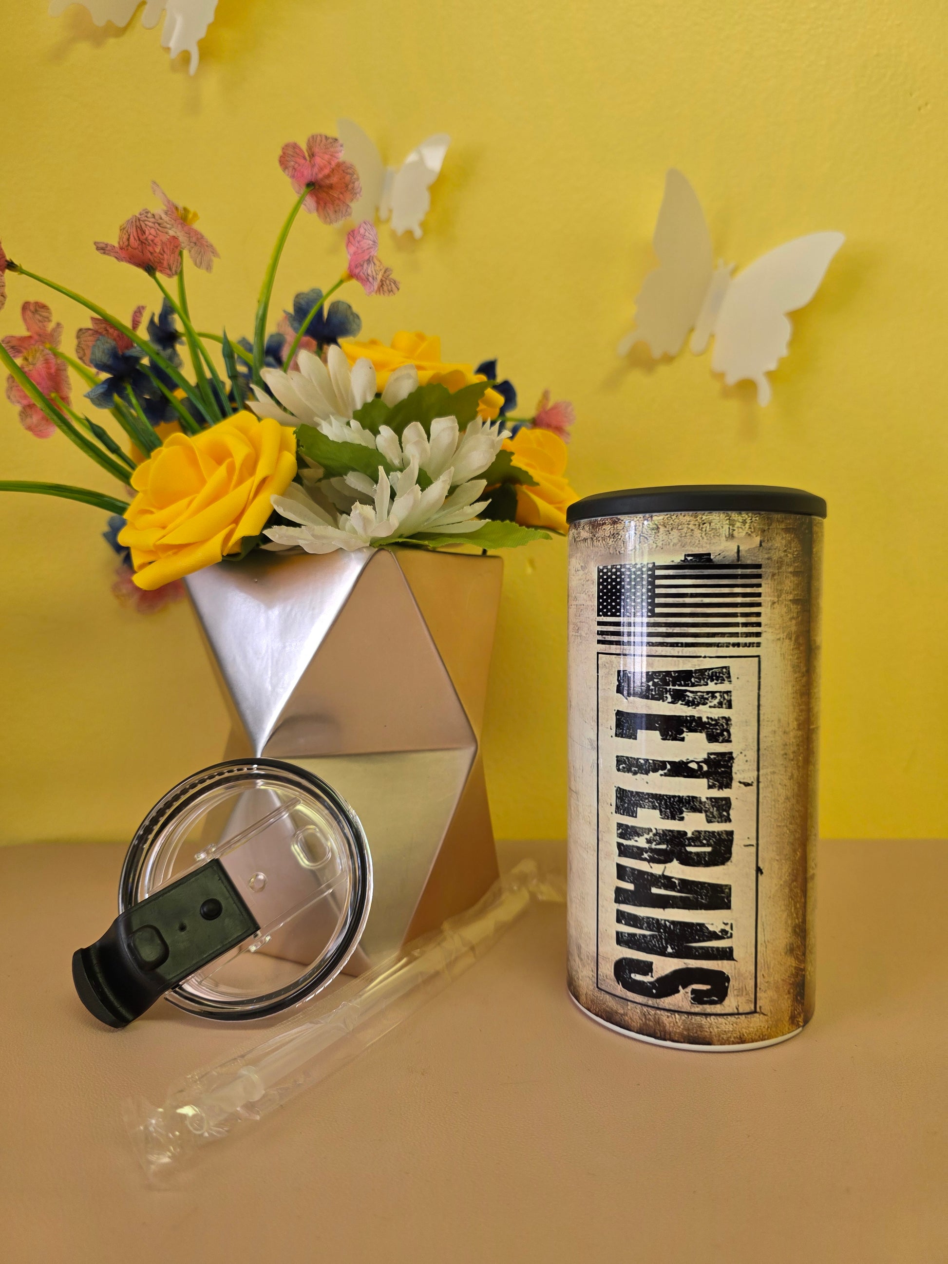4‑in‑1 insulated stainless steel tumbler with rustic Veterans American flag design, shown with lid, straw, and patriotic decor