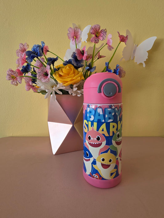 Baby Shark kids water bottle tumbler on a table with flowers in the background