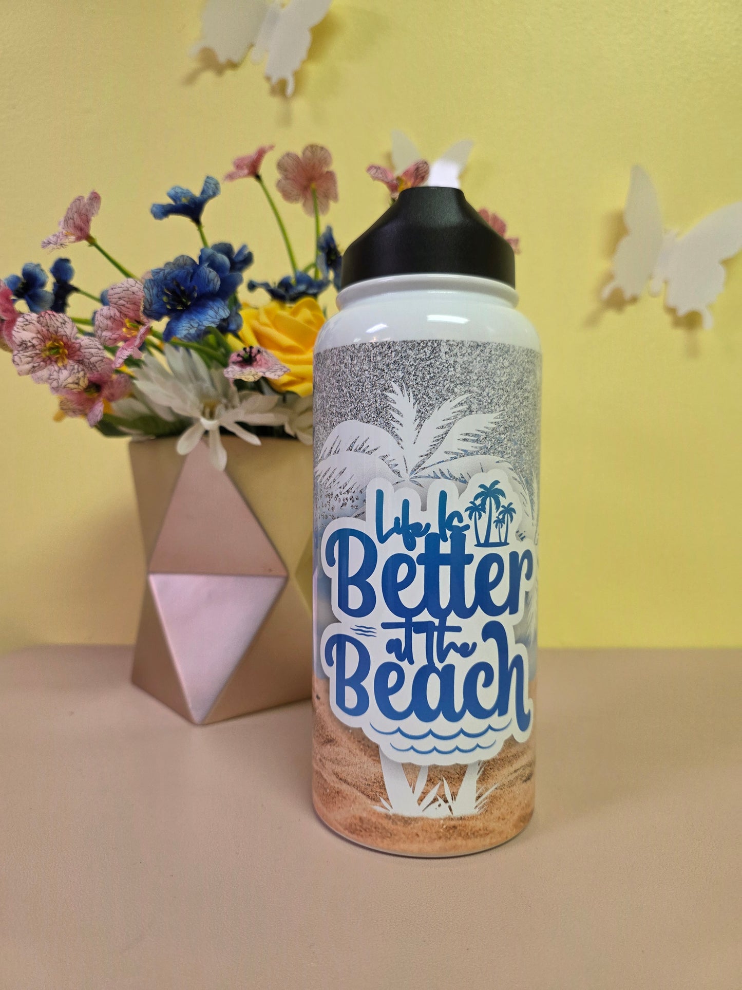 Bottle labeled 'Better at the Beach' with flowers on a yellow and beige background