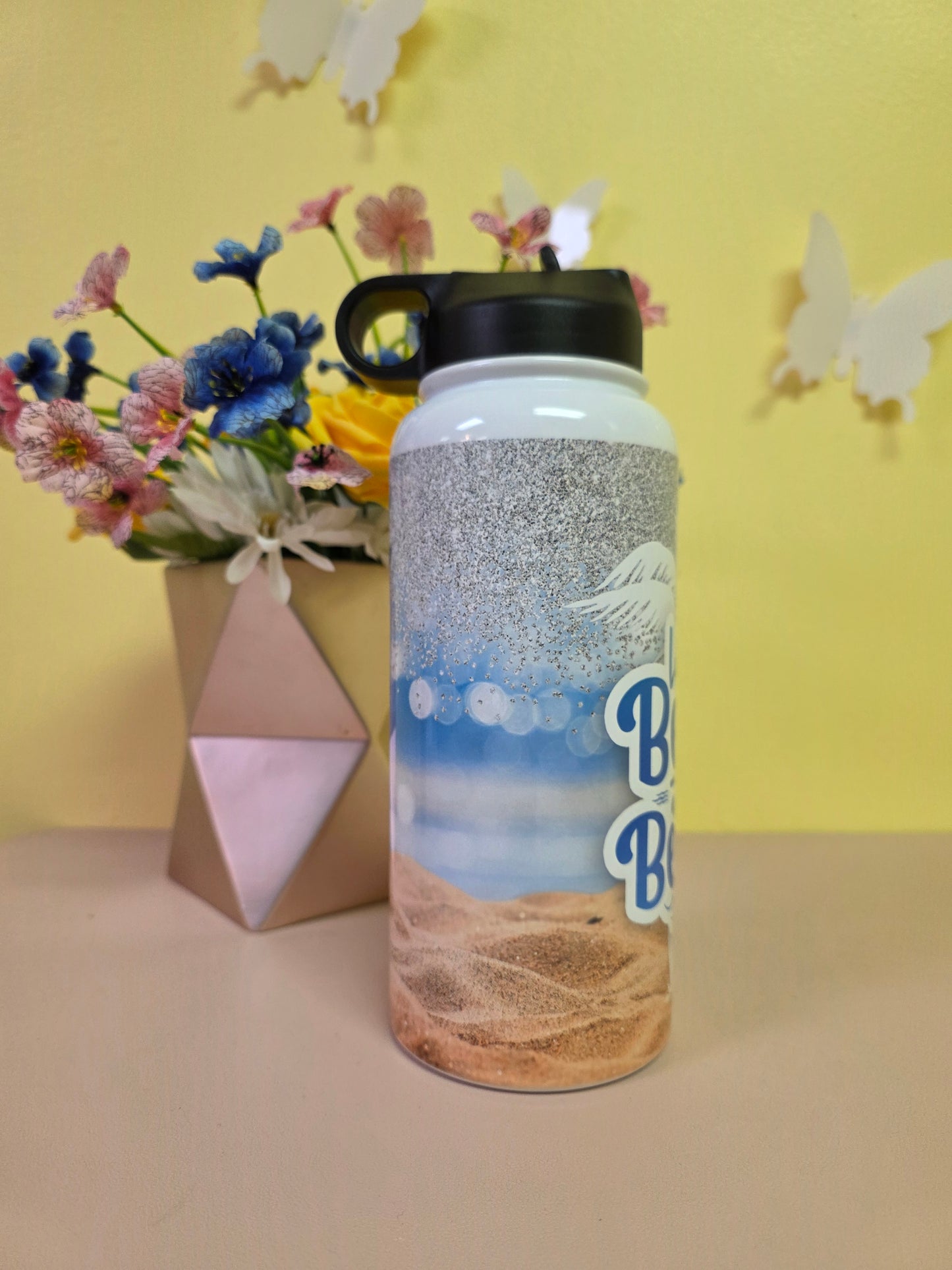 Tumbler with floral arrangement and geometric box on a yellow background