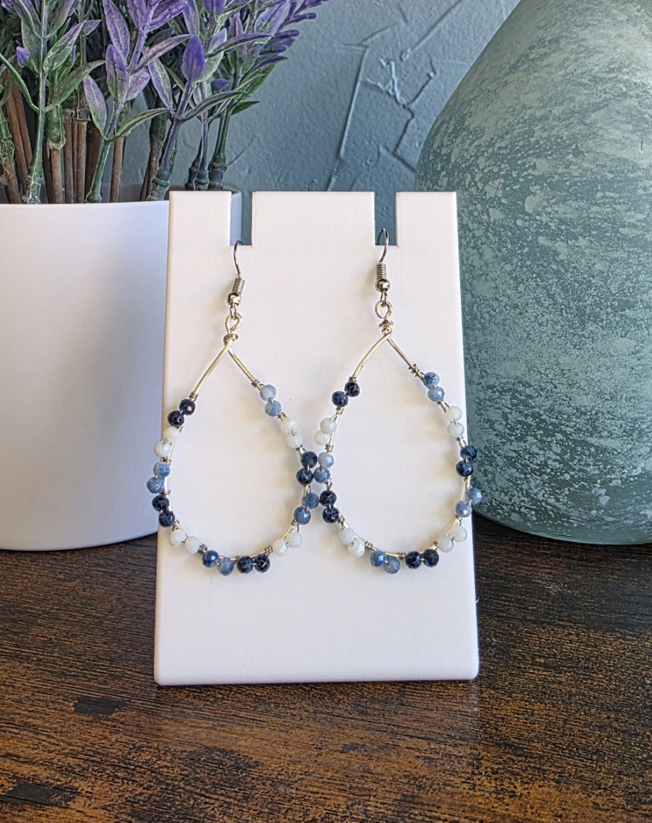 Pair of beaded earrings on a white card with a blurred background