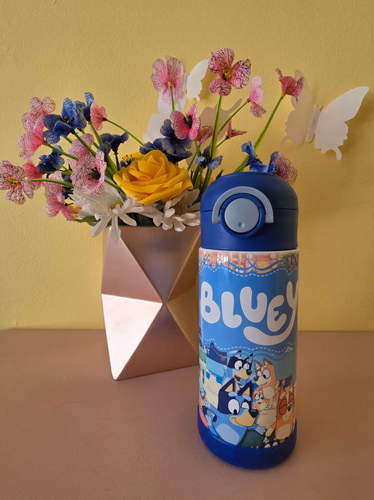 Bluey tumbler water bottle with lid and straw on a table with flowers in the background 