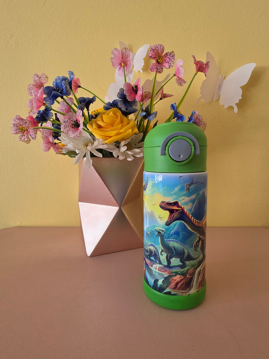 Dinosaurs print stainless steel water bottle for kids on a table with flowers in the background. 