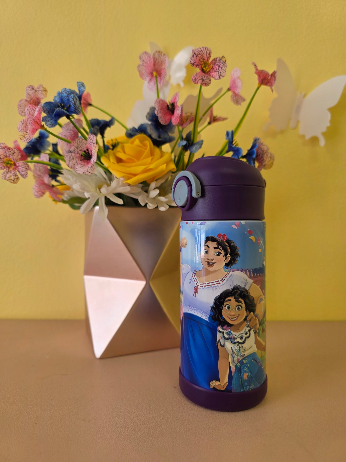 Tumbler with cartoon characters on a yellow background with flowers
