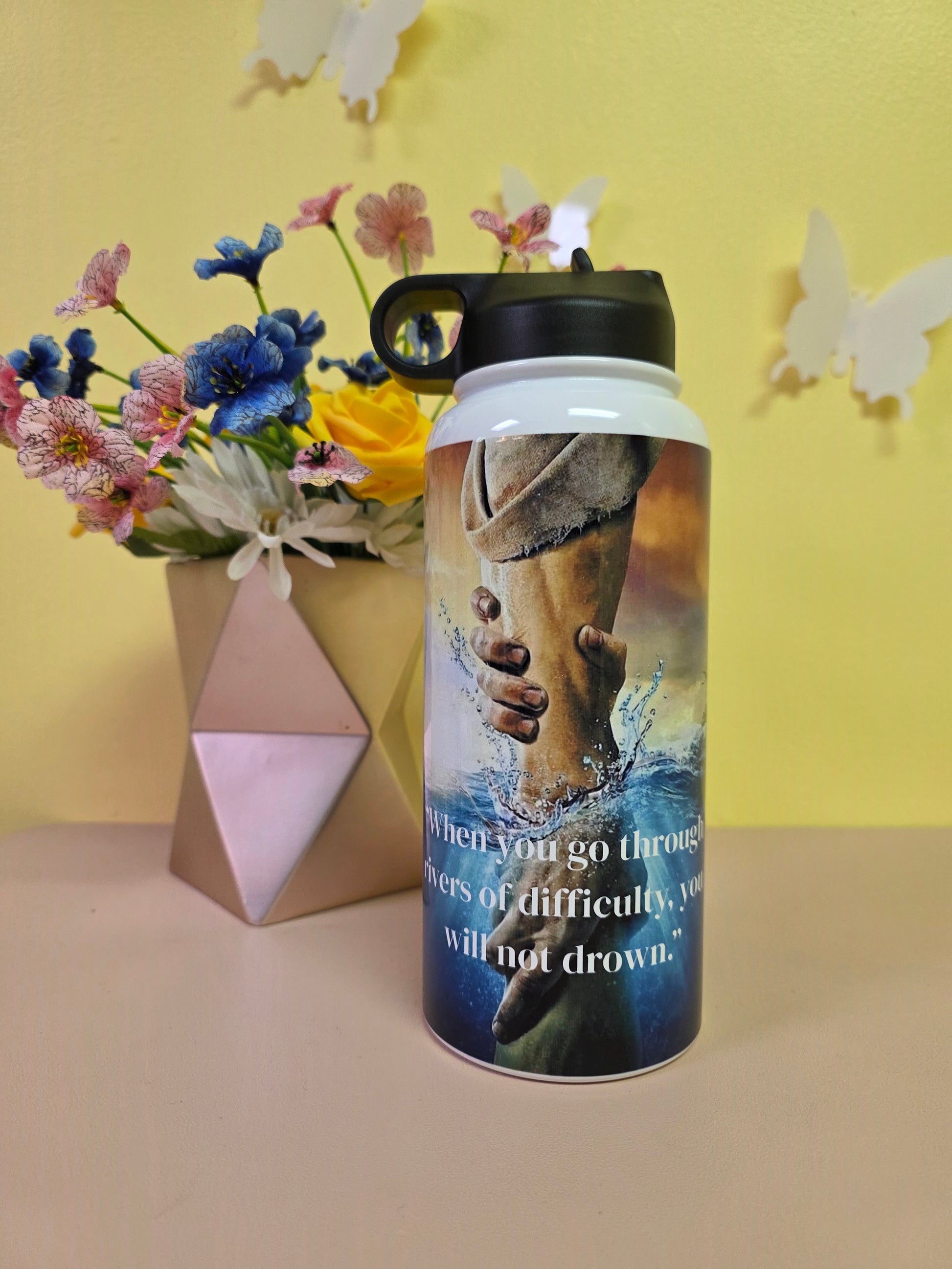 Tumbler with a design of hands holding flowers against a yellow background