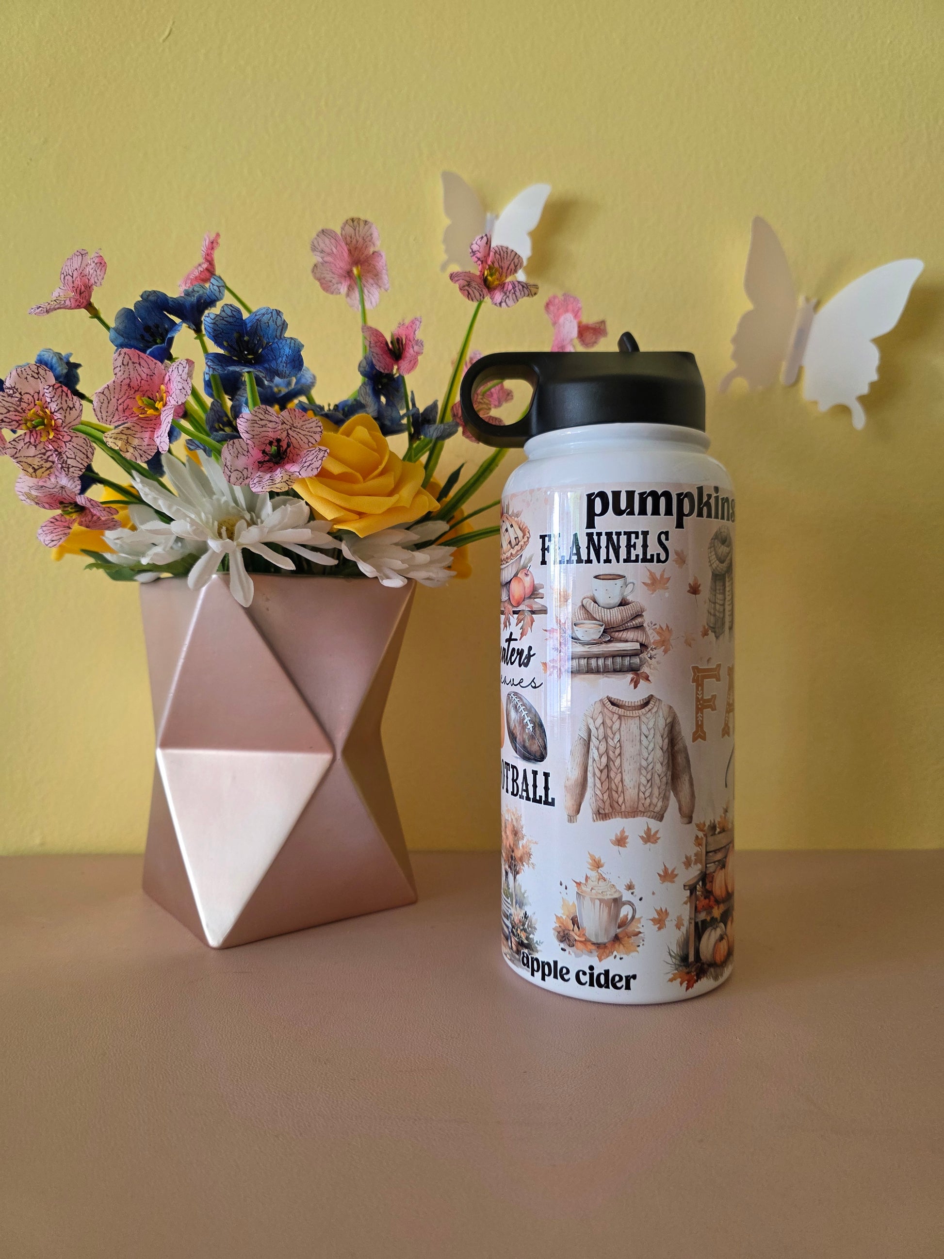 Fall themed water bottle on a table with yellow background