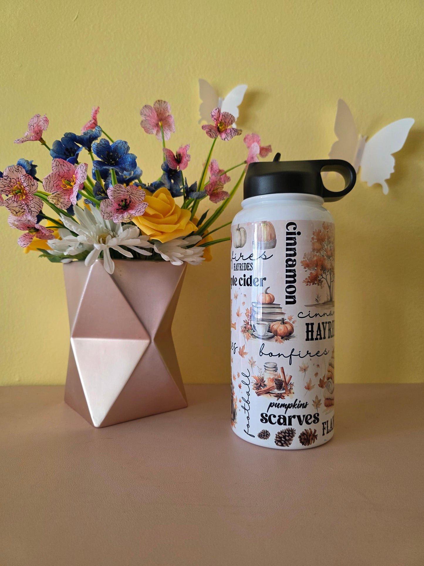 Fall themed water bottle on a table with yellow background