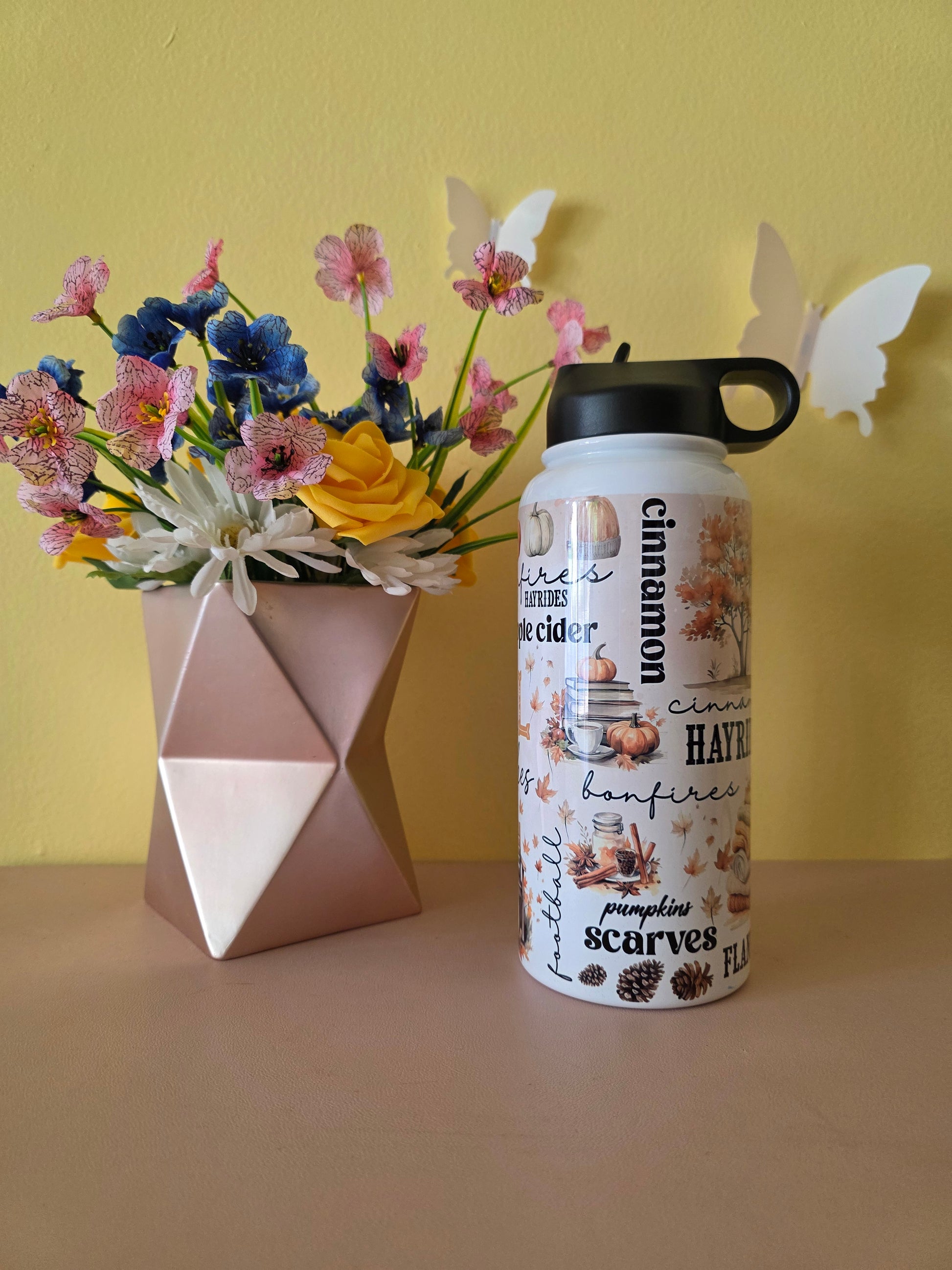 Fall themed water bottle on a table with yellow background