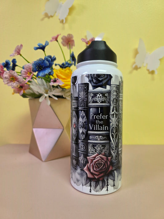 Bottle with decorative label on a yellow surface with flowers and a box.