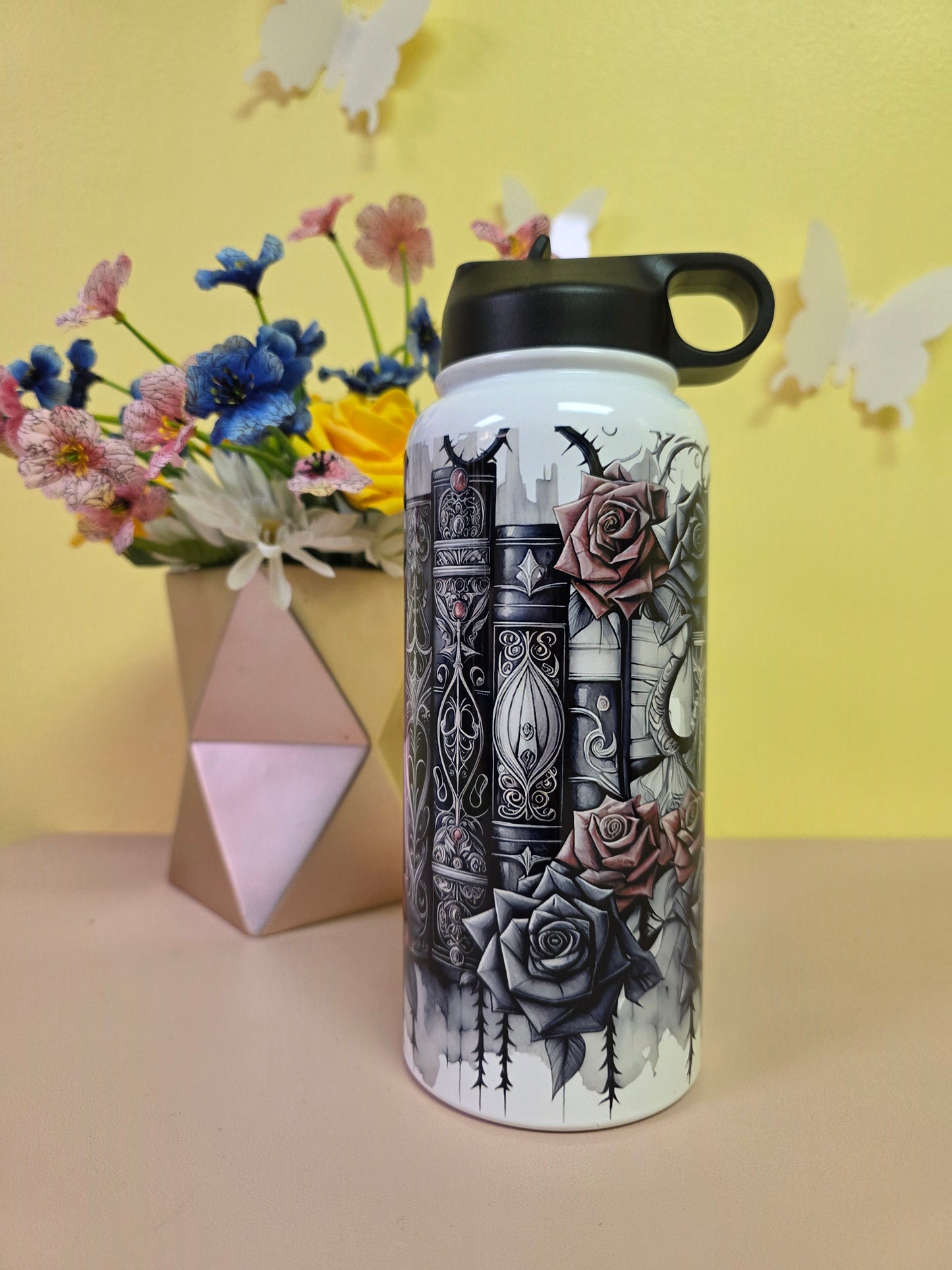 Water bottle with intricate design on a yellow background with flowers and a box.
