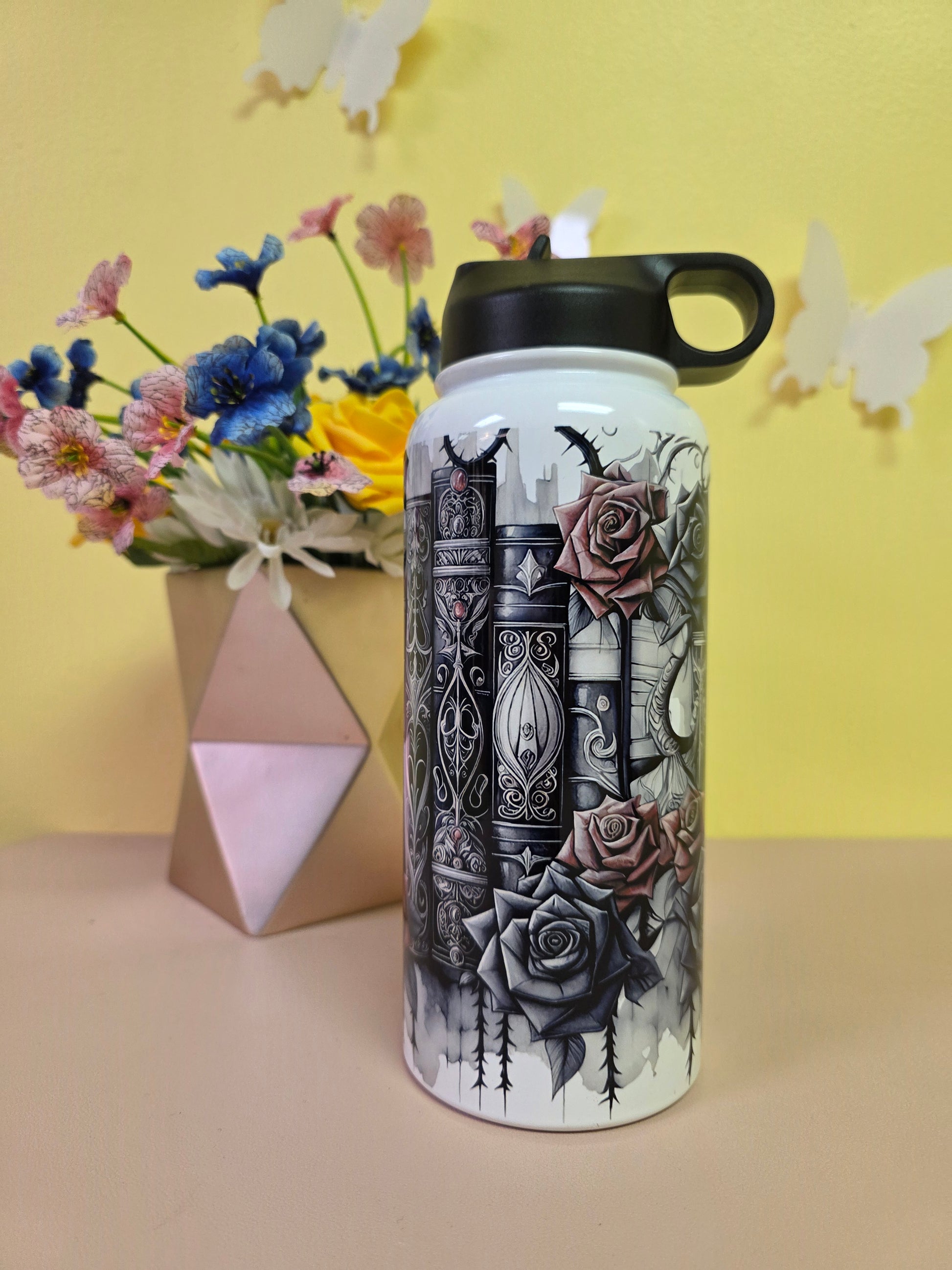 Water bottle with intricate design on a yellow background with flowers and a box.
