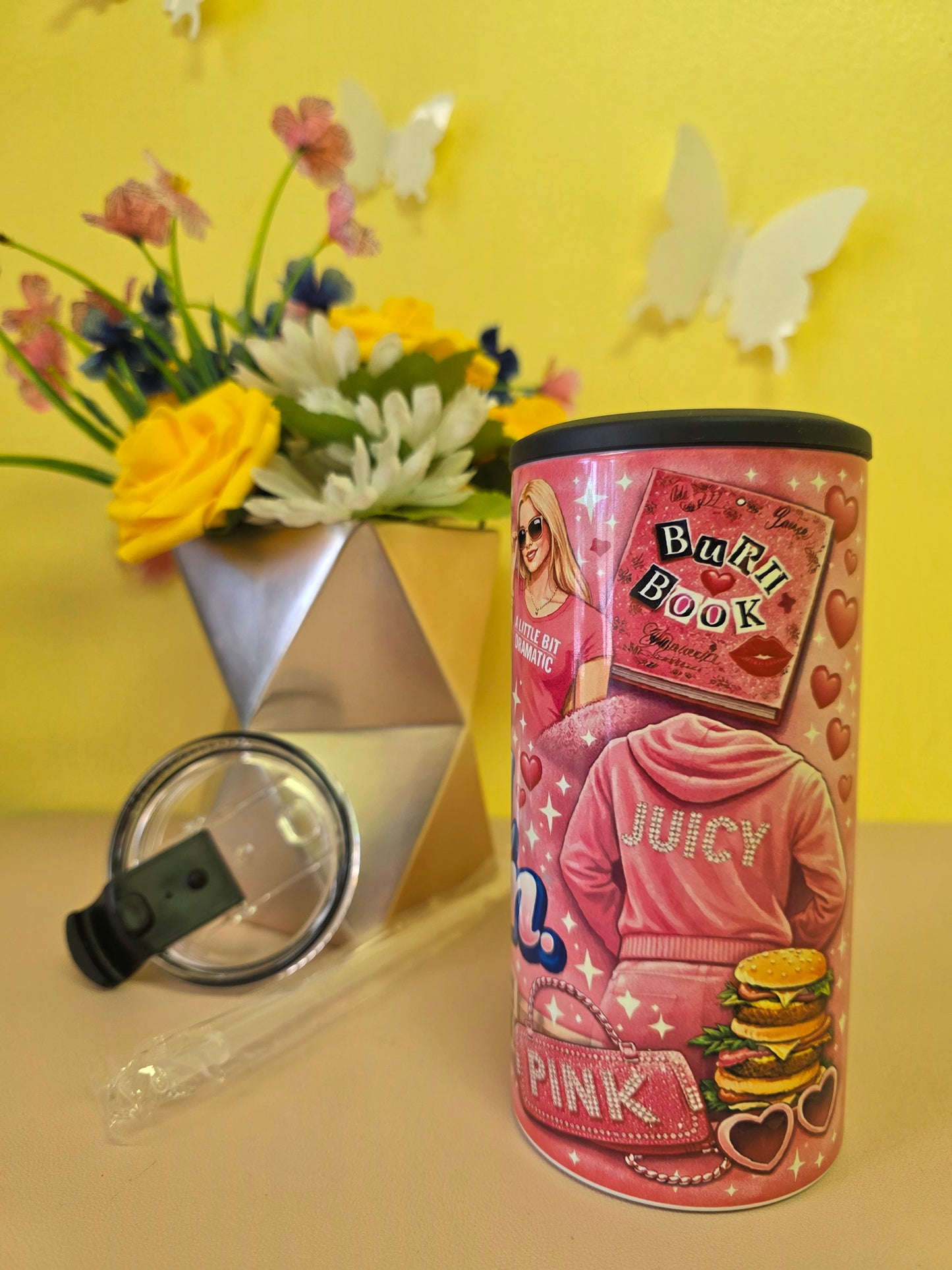 Pink insulated stainless steel tumbler with ‘I’m not a regular mom I’m a cool mom’ design, clear lid, straw, and floral background decor