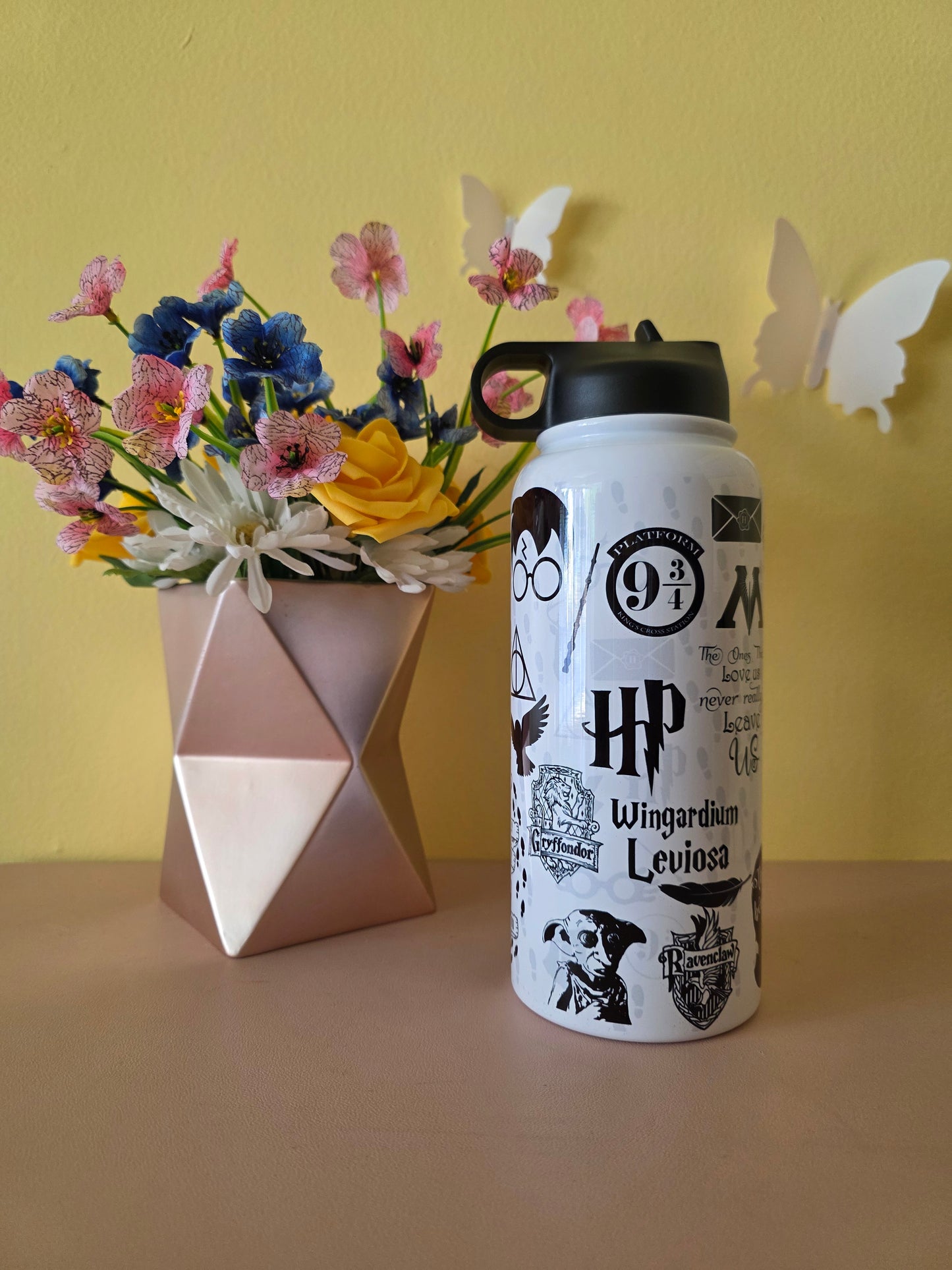 Harry Potter themed stainless steel water bottle on a table with yellow background