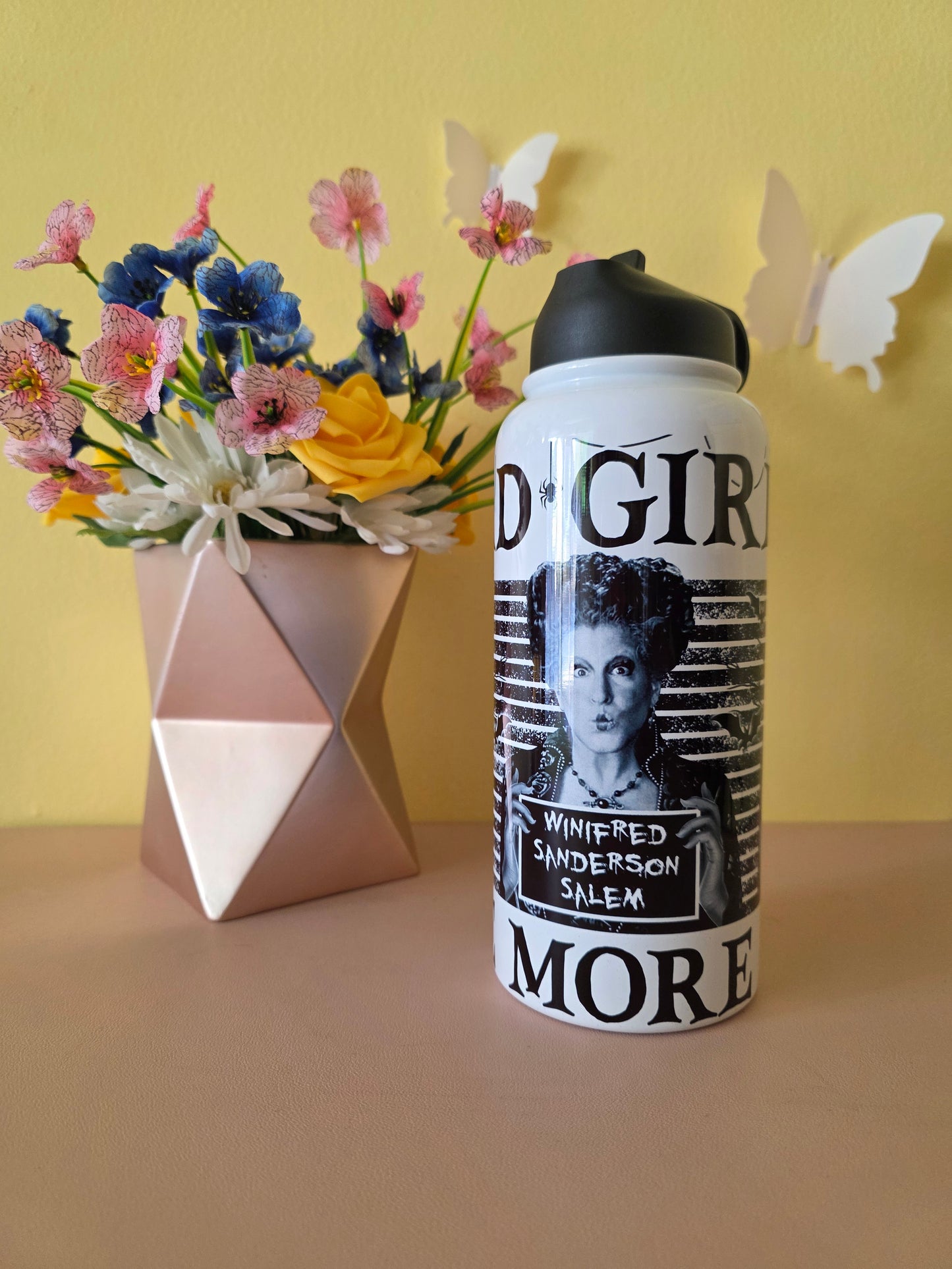Hocus Pocus water bottle on a pink table with yellow background with flowers