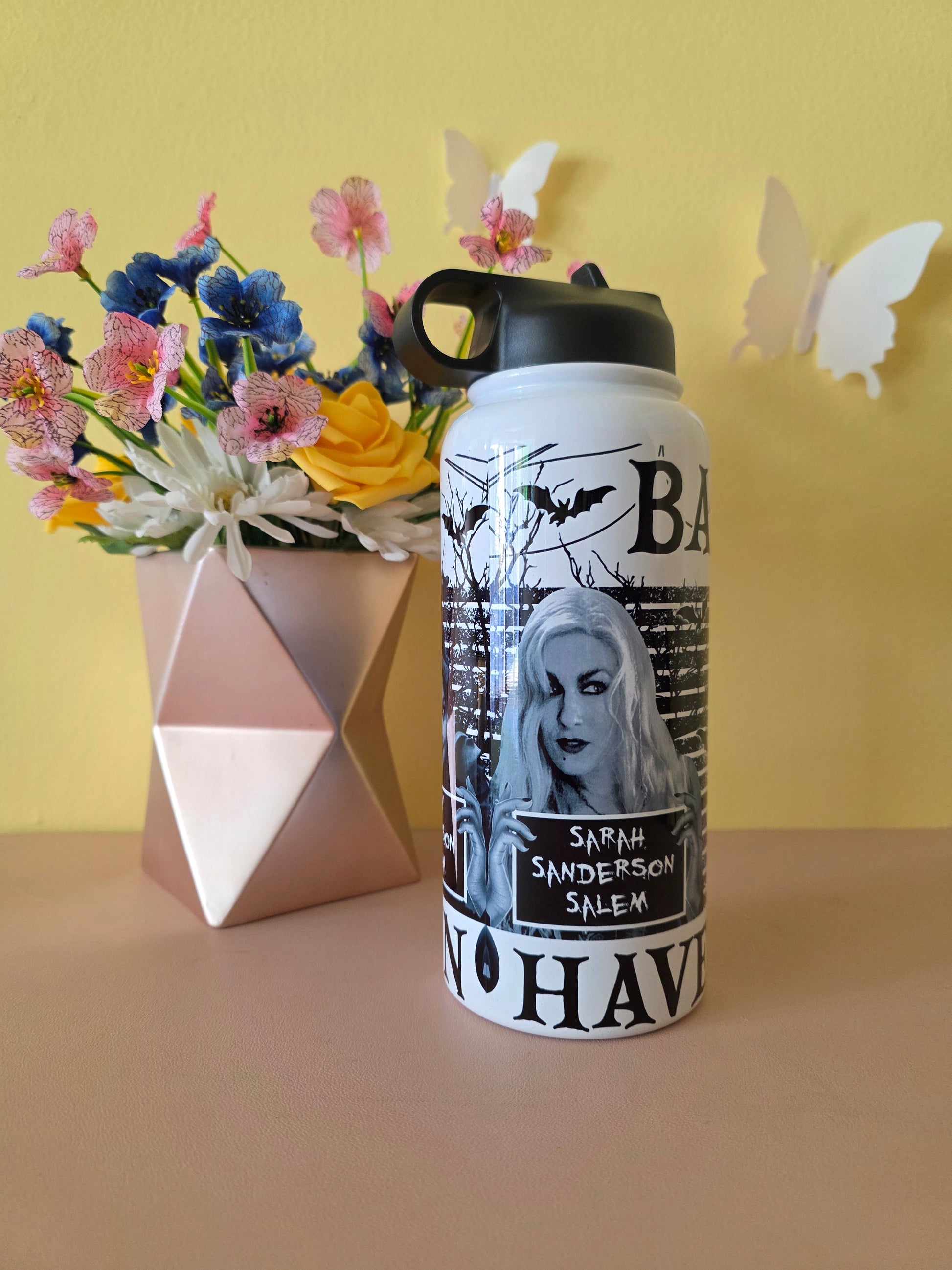 Hocus Pocus water bottle on a pink table with yellow background with flowers