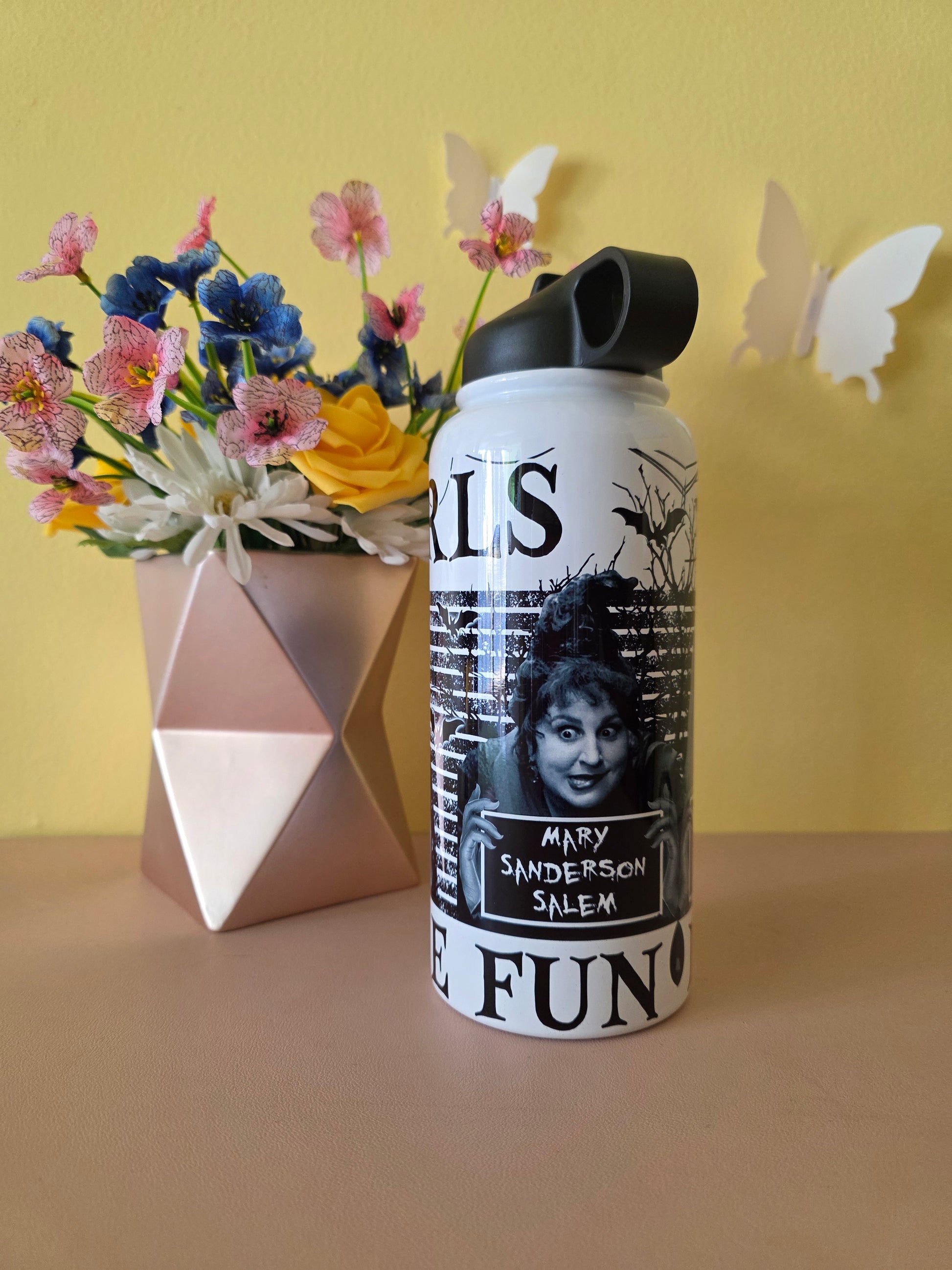 Hocus Pocus water bottle on a pink table with yellow background with flowers