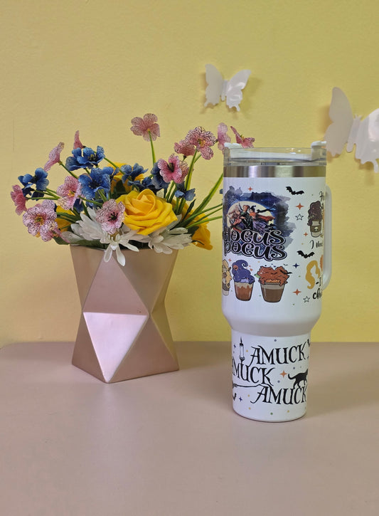 Tumbler with decorative design next to a bouquet of flowers on a yellow background