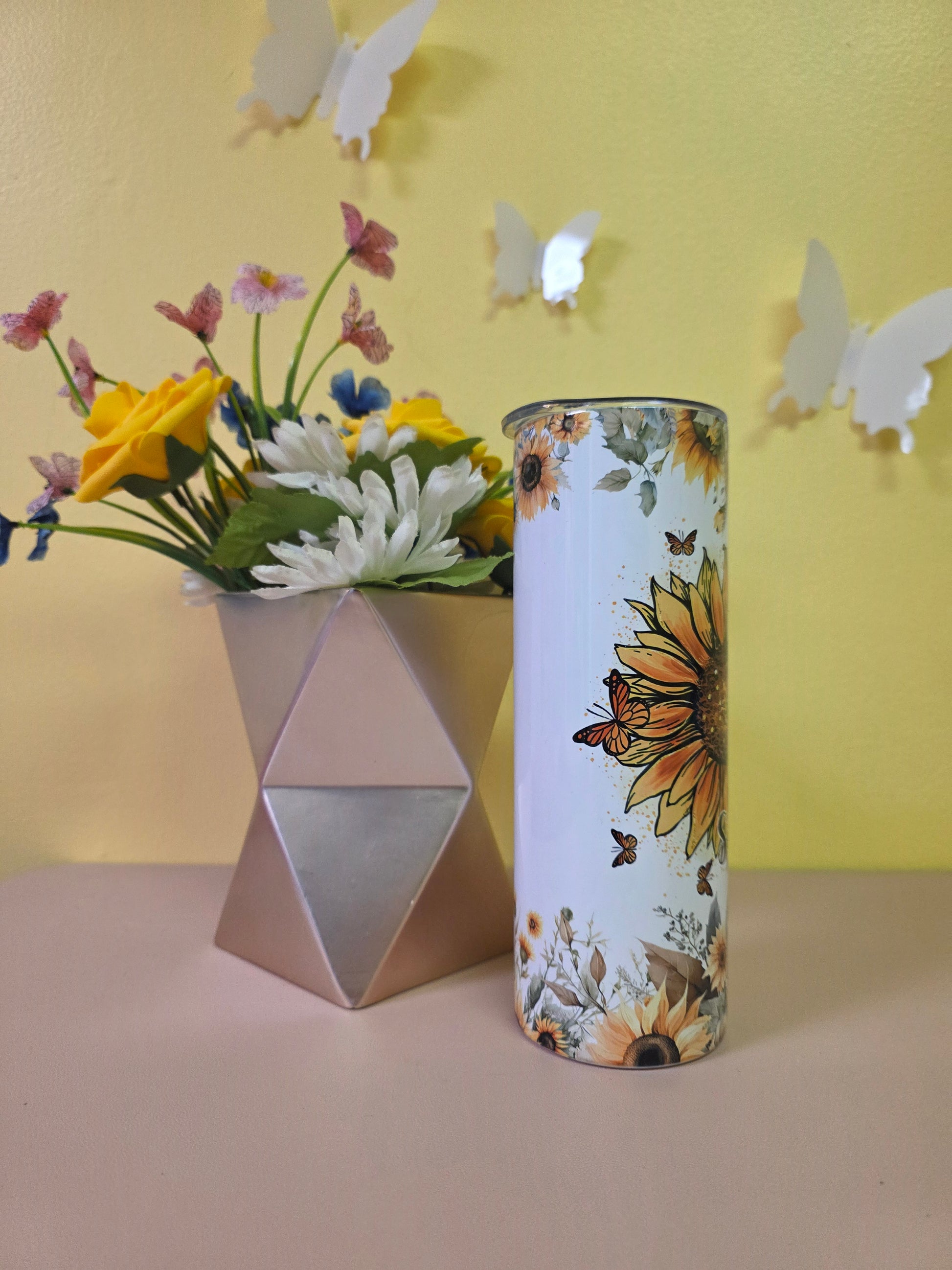 Floral-patterned cylindrical container with a geometric pink object on a yellow background