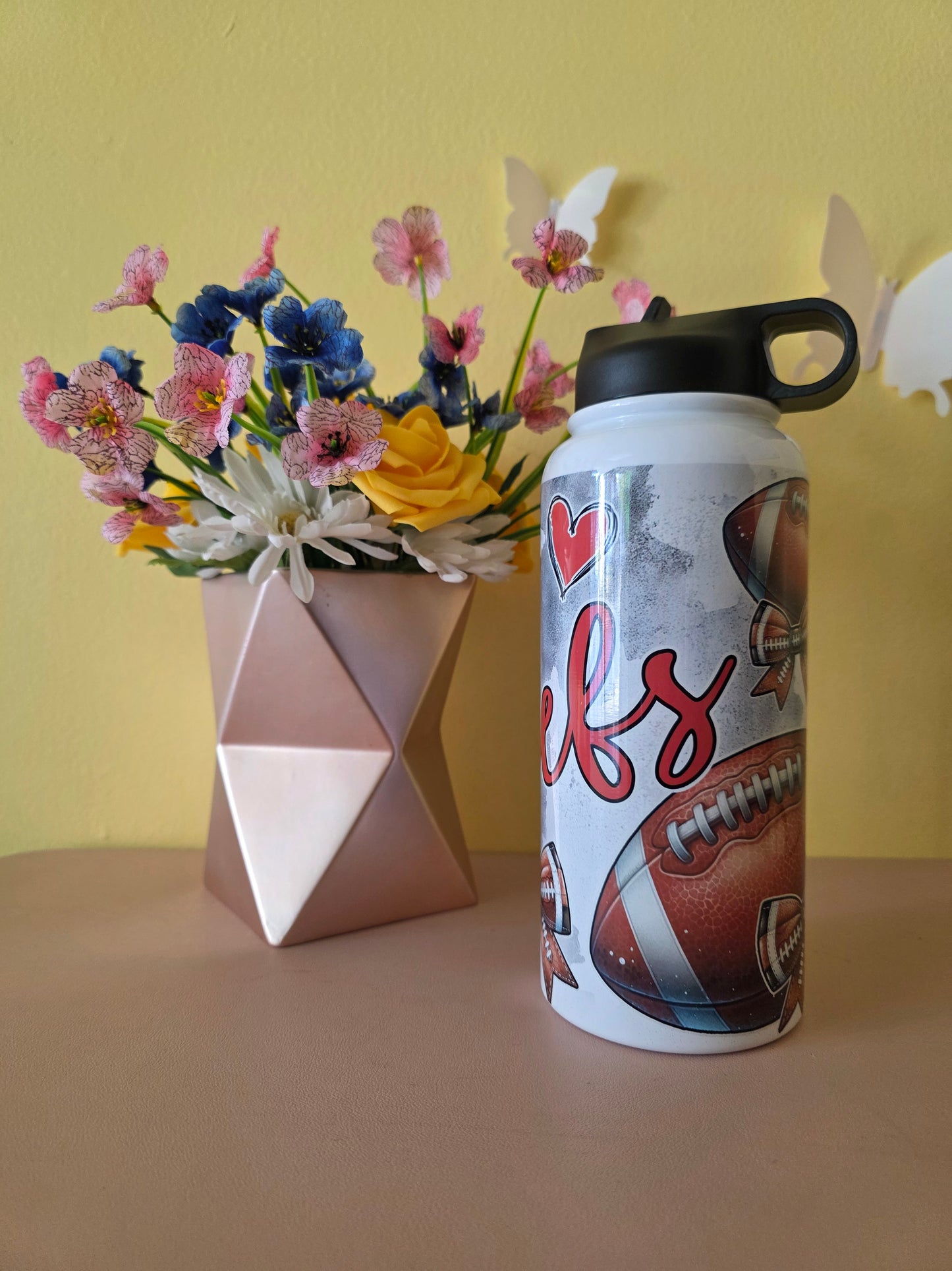 Kansas City Chiefs Football water bottle on a table with yellow background