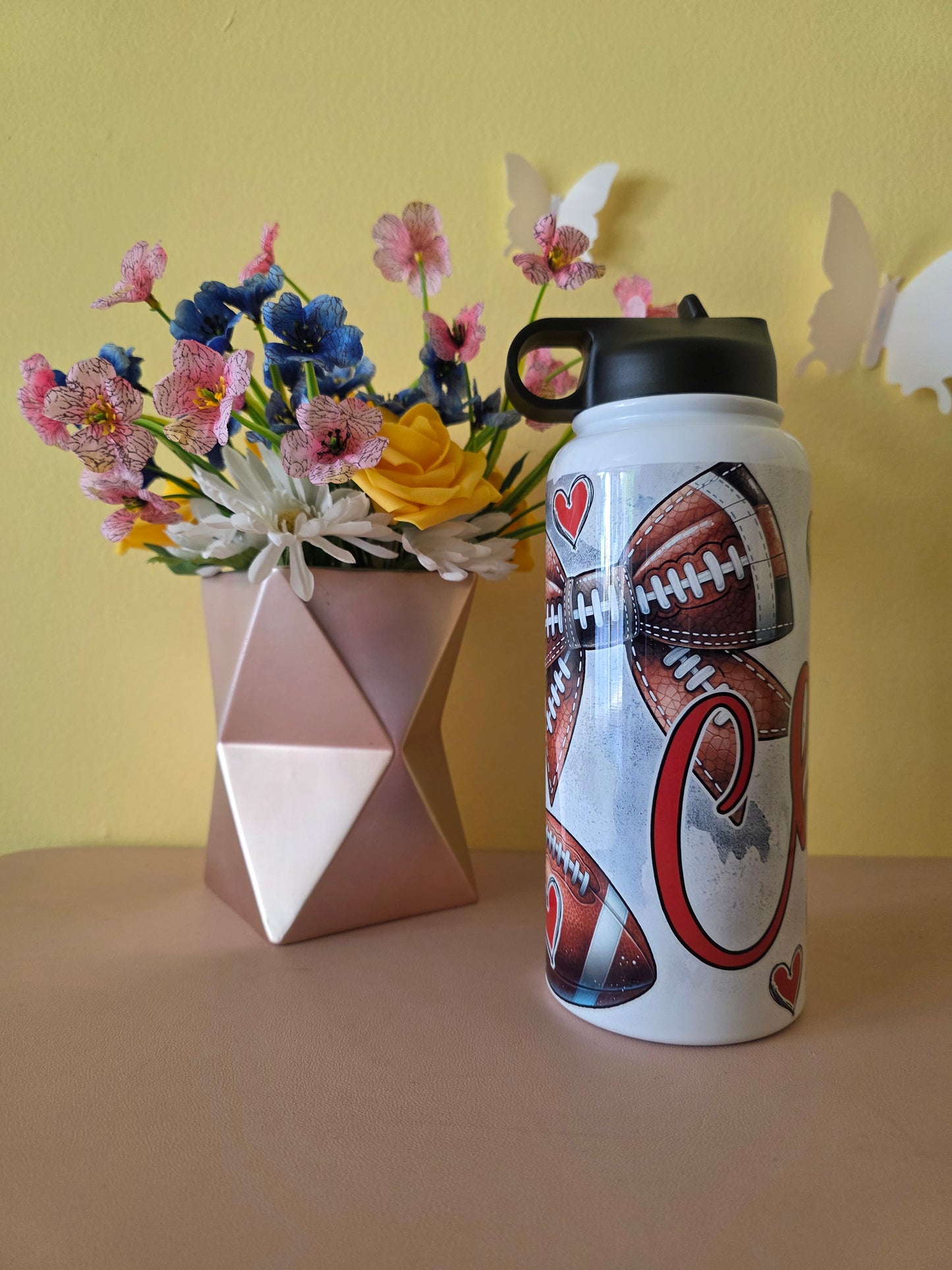 Kansas City Chiefs Football water bottle on a table with yellow background