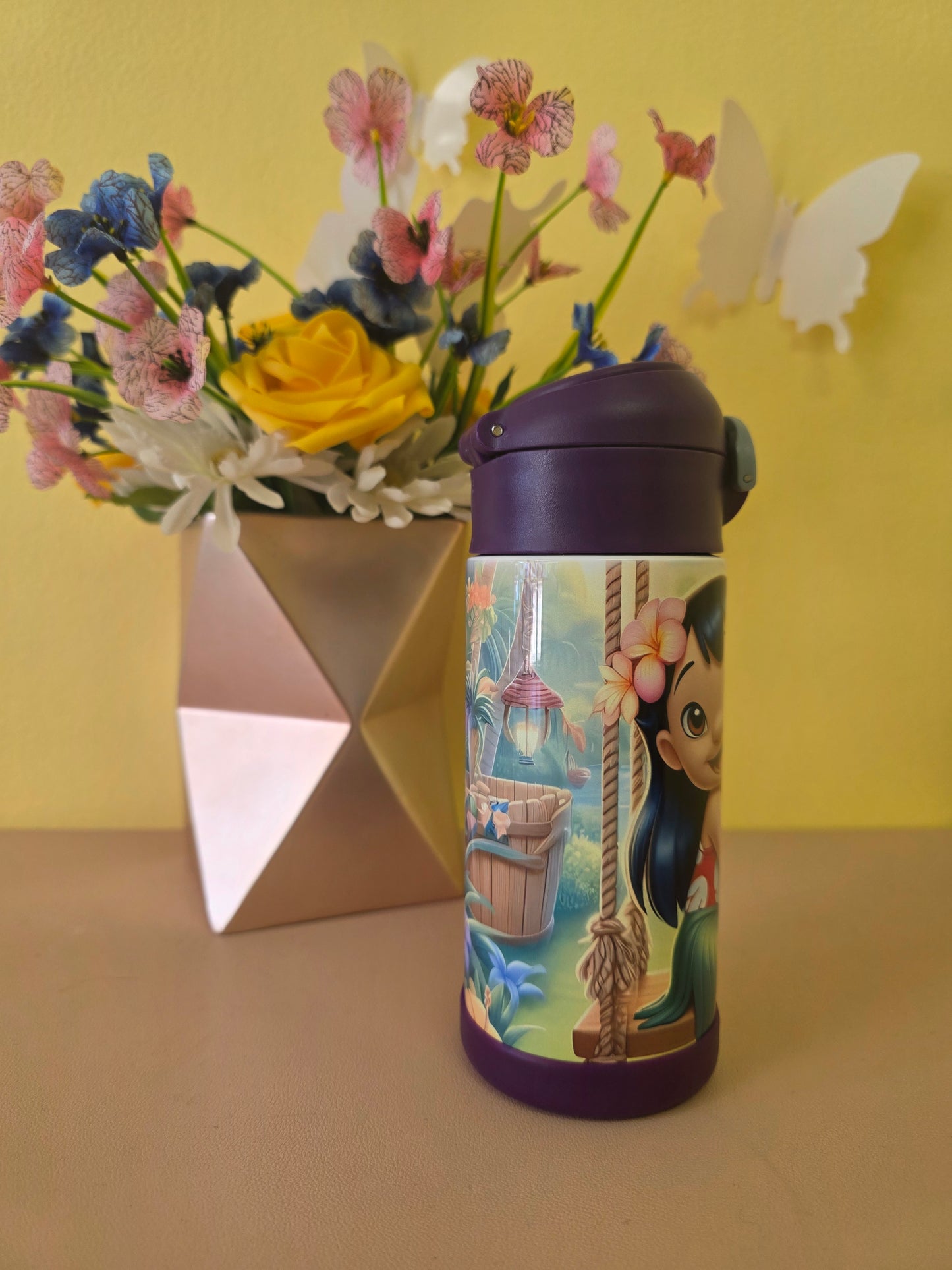 Lilo and Stitch tumbler on a table with flowers in the background. 