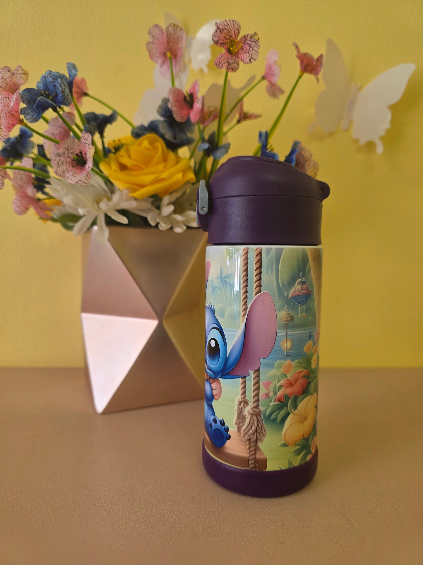 Lilo and Stitch tumbler on a table with flowers in the background. 