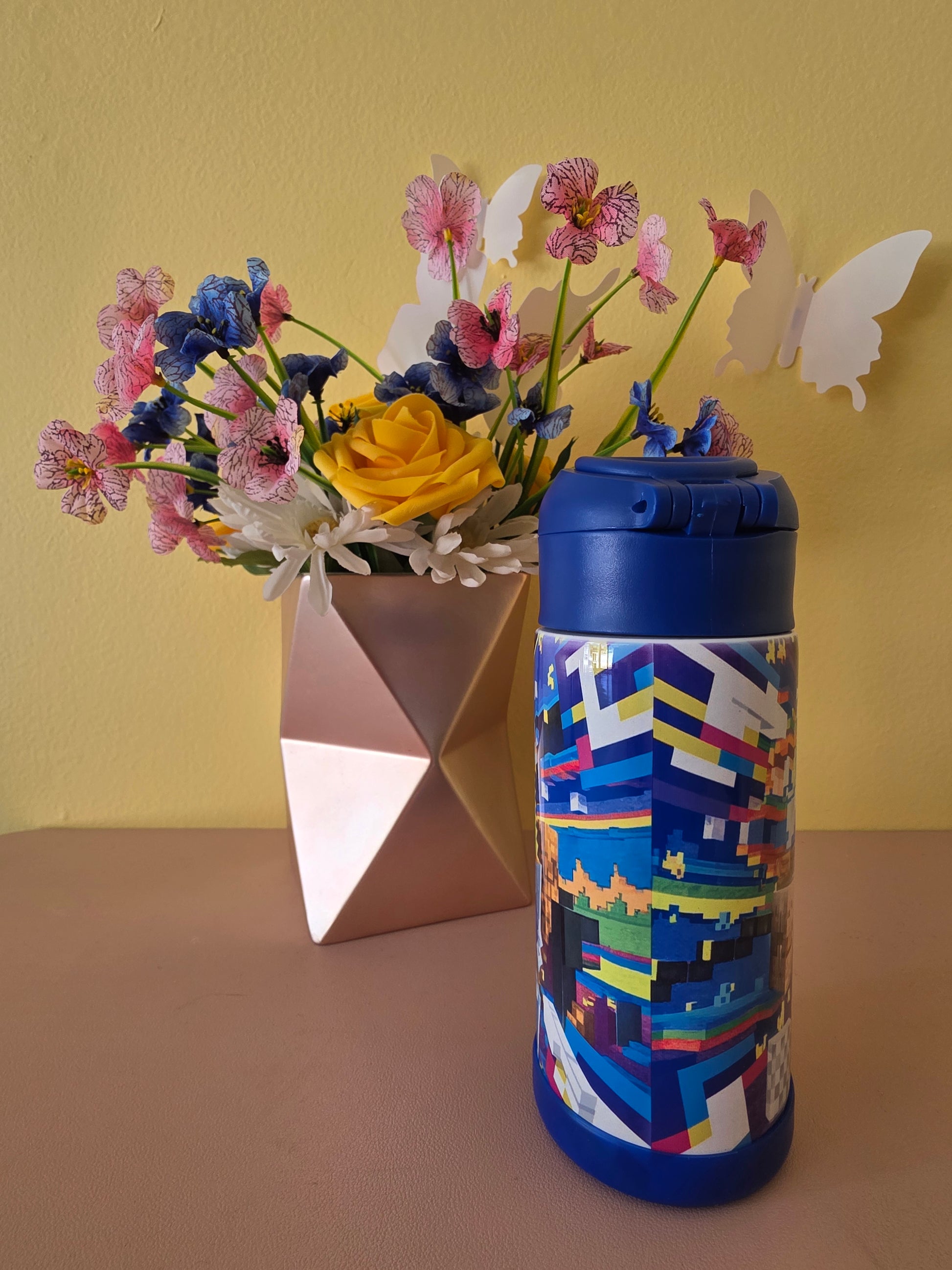 Minecraft stainless steel water bottle for kids on a table with flowers in the background. 