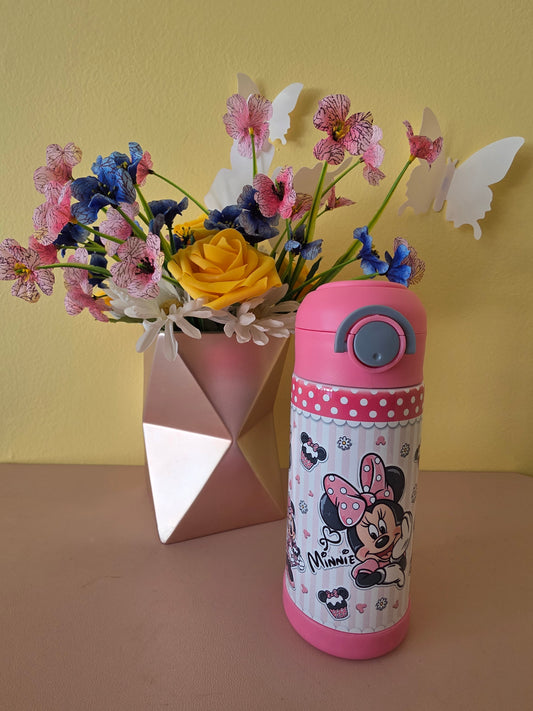 Pink Minnie Mouse tumbler for kids ion a table with flowers in the background. 