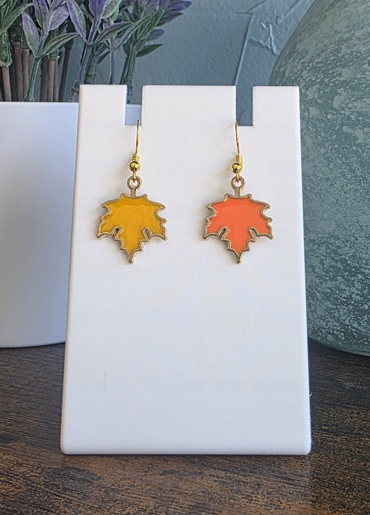 Pair of leaf-shaped earrings on a white stand with a blurred background