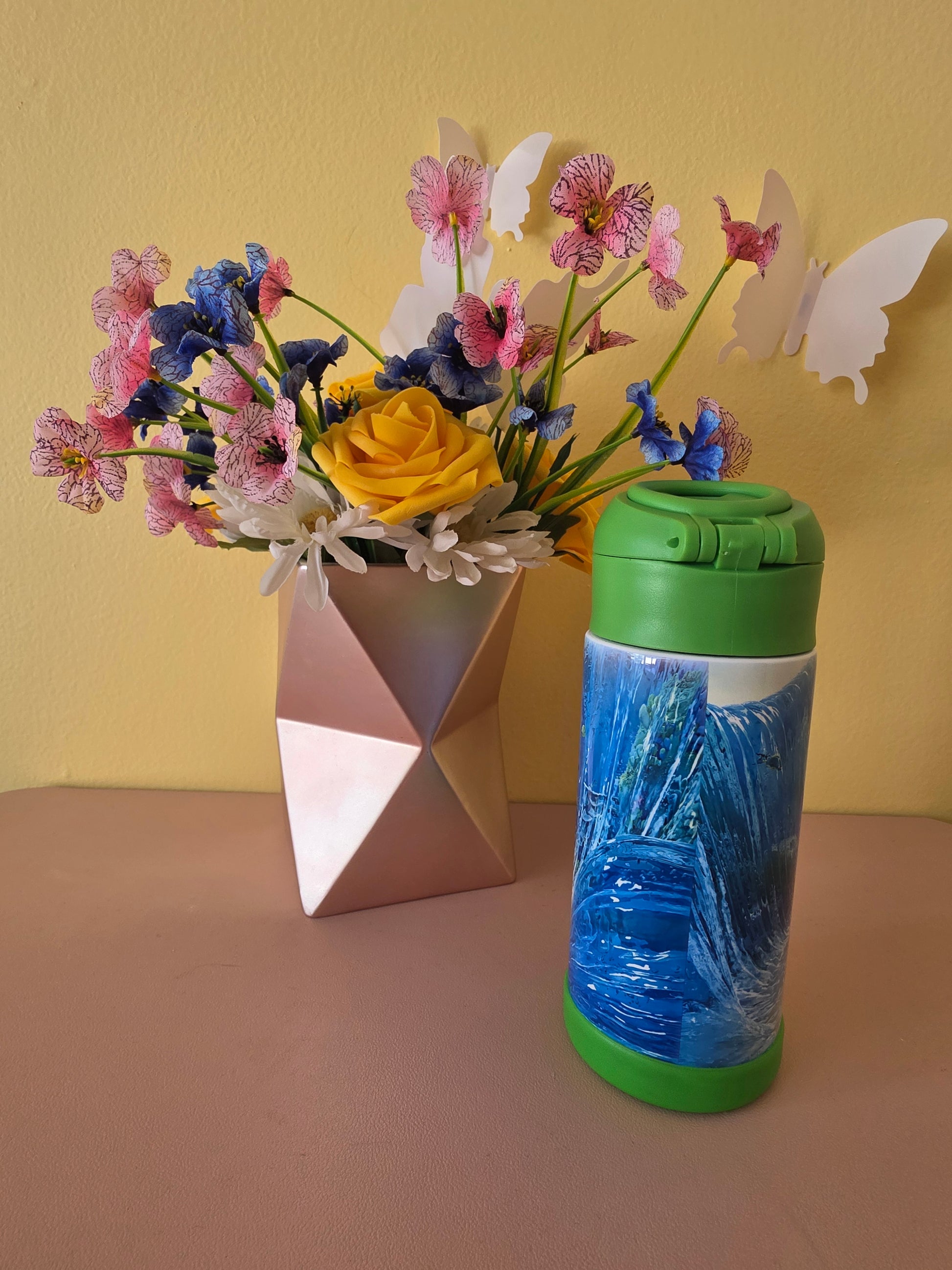 Moana and Maui Tumbler on a table with flowers in the background. 