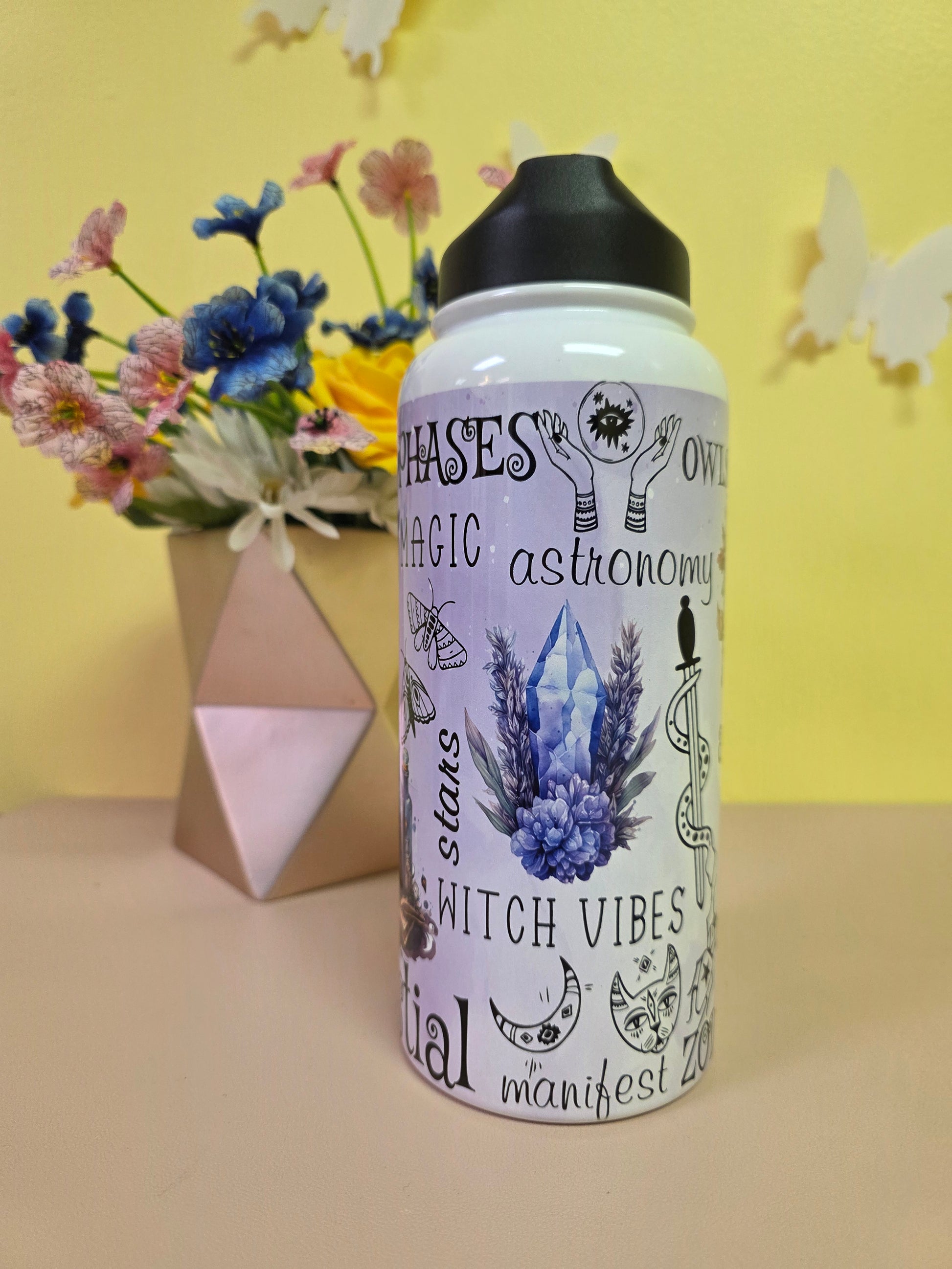 Metaphysical crystal water bottle on a pink table with yellow background. 