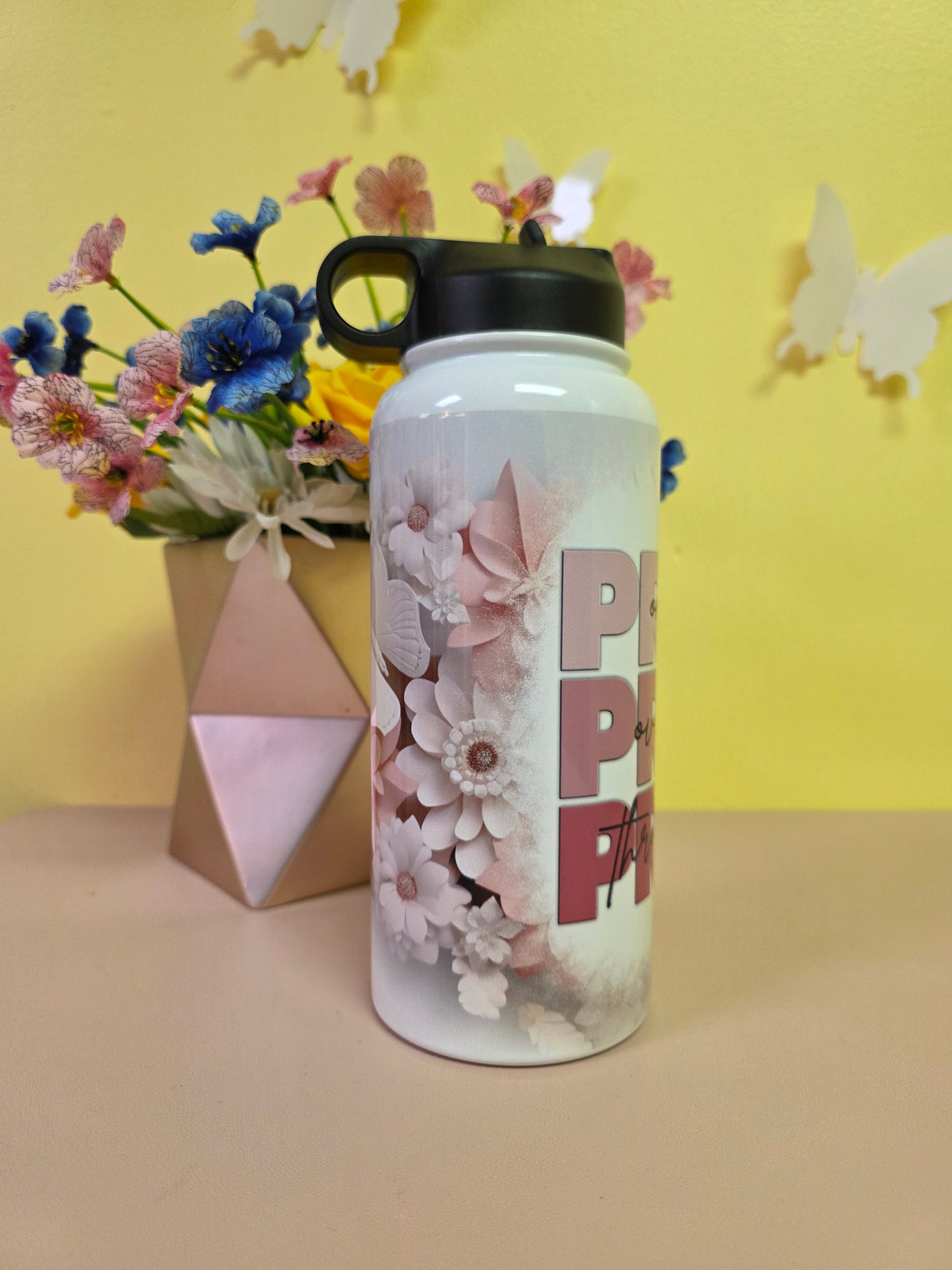 Water bottle with a prayer design on a table with yellow background. 