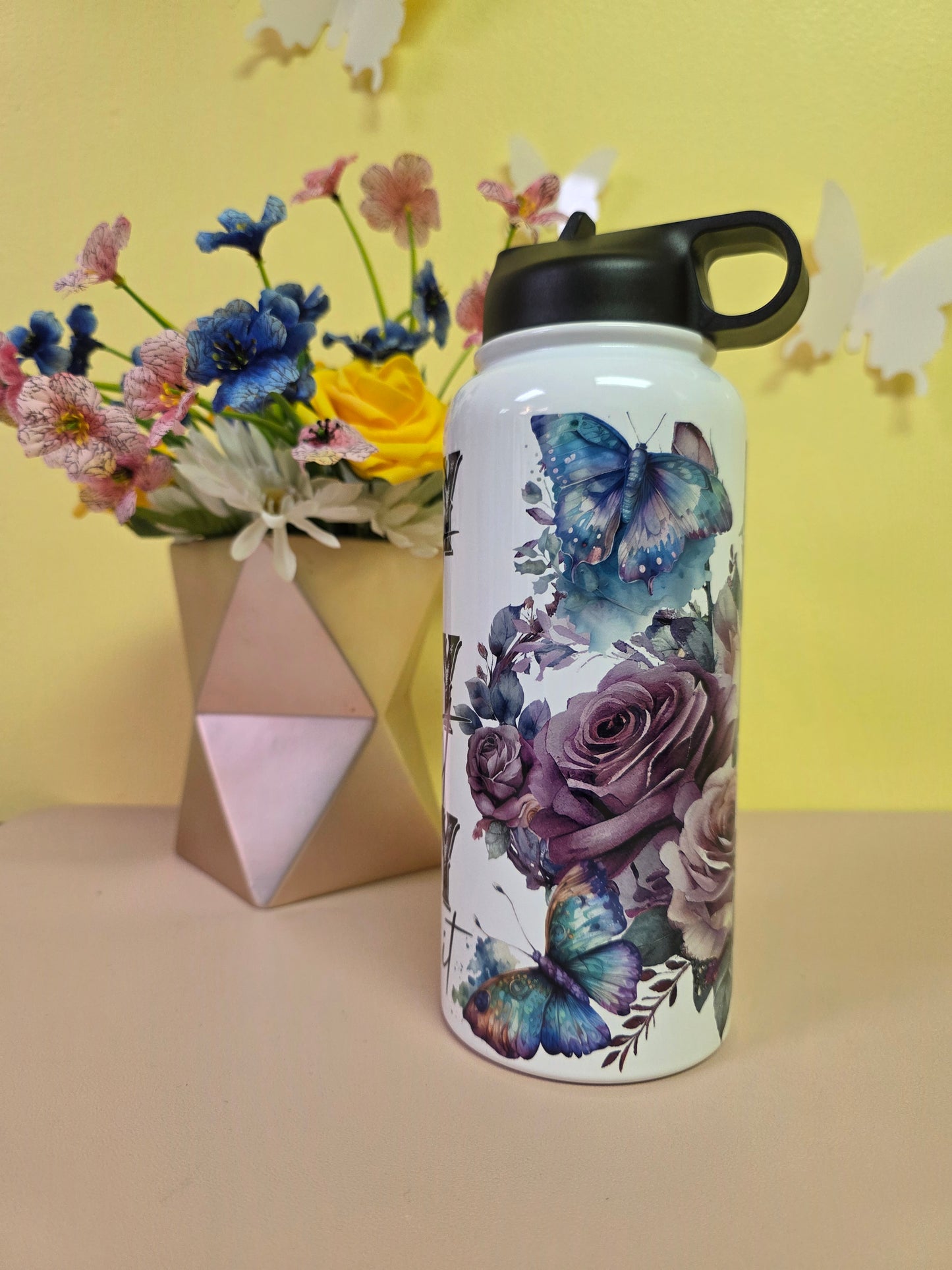 Water bottle with 'PRAY' text on a yellow background with flowers