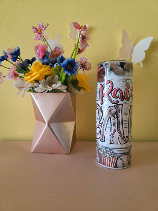 Decorative tumbler with colorful baseball design on a pink surface and yellow background