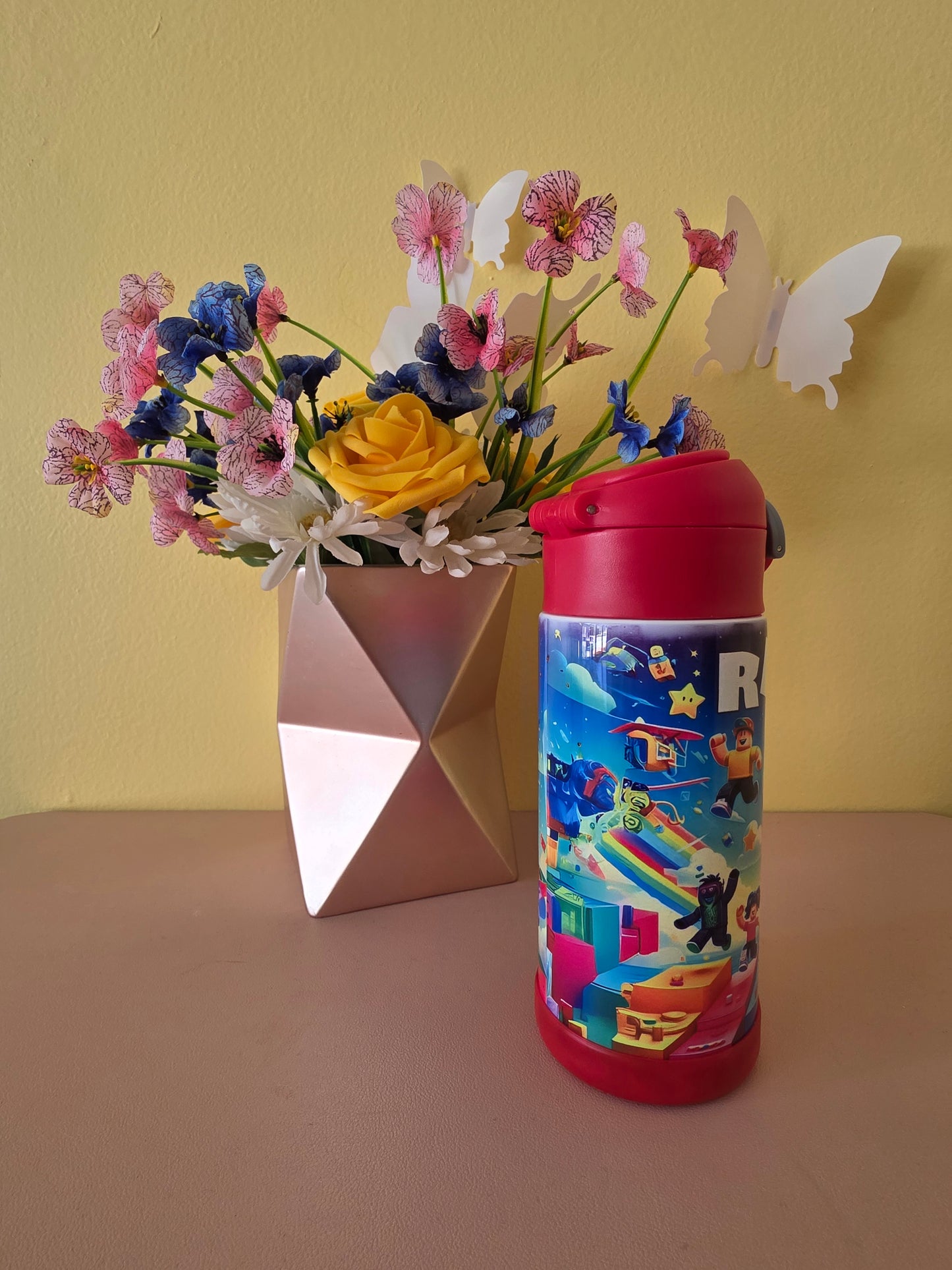 Roblox Stainless Steel Tumbler for kids on a table with flowers in the background. 