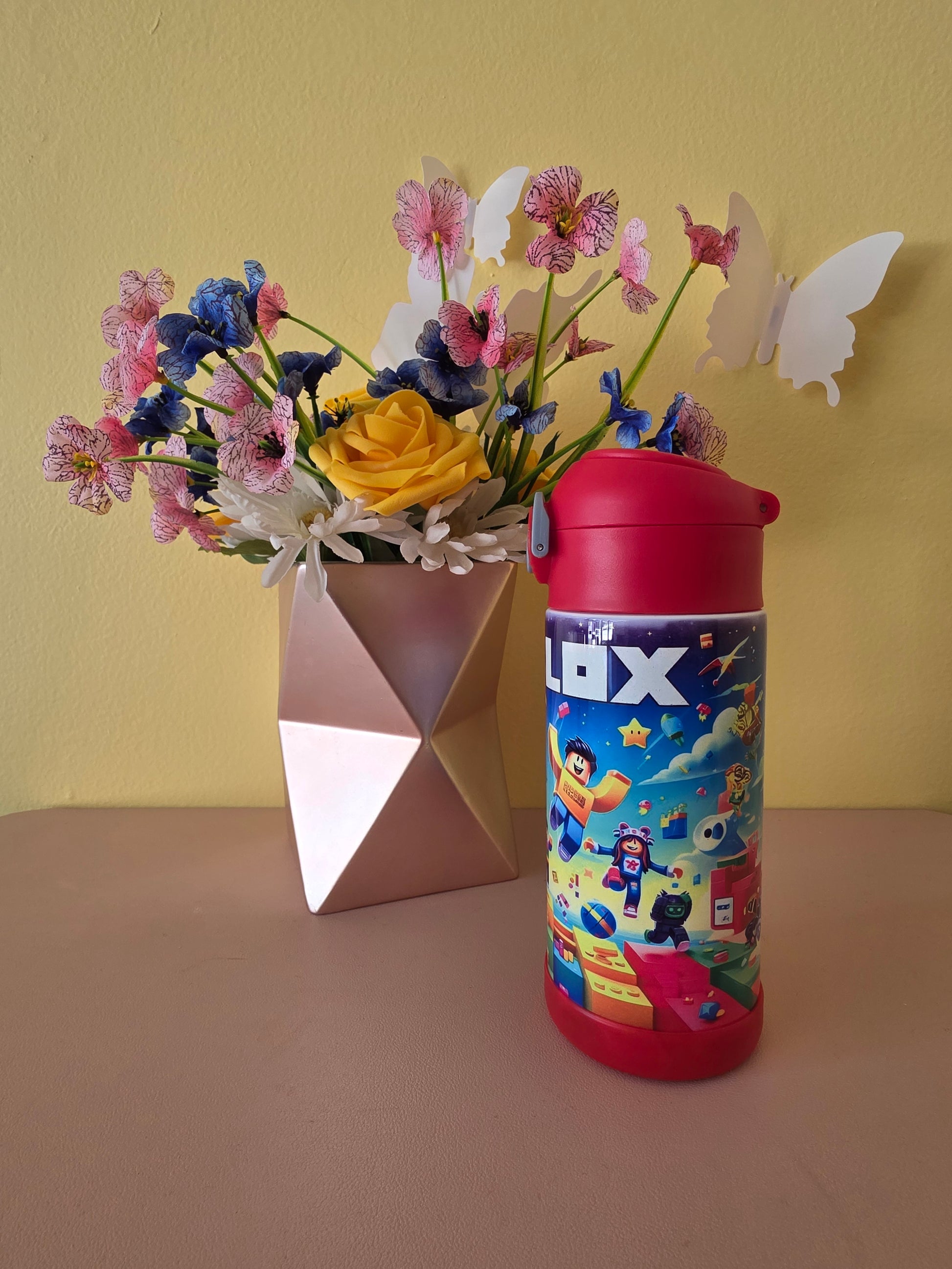 Roblox Stainless Steel Tumbler for kids on a table with flowers in the background. 