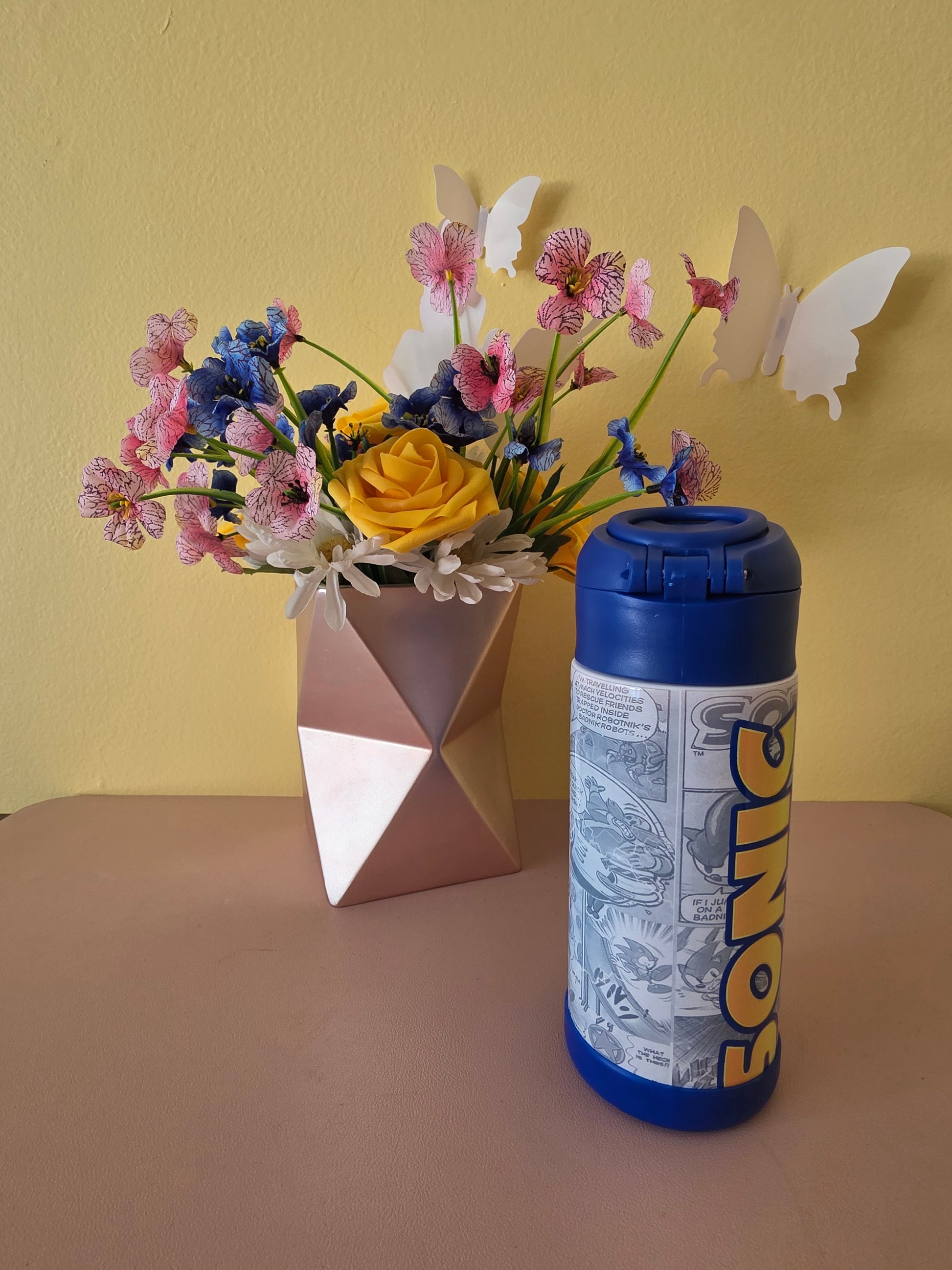 Sonic the Hedgehog tumbler on a table with flowers in the background. 