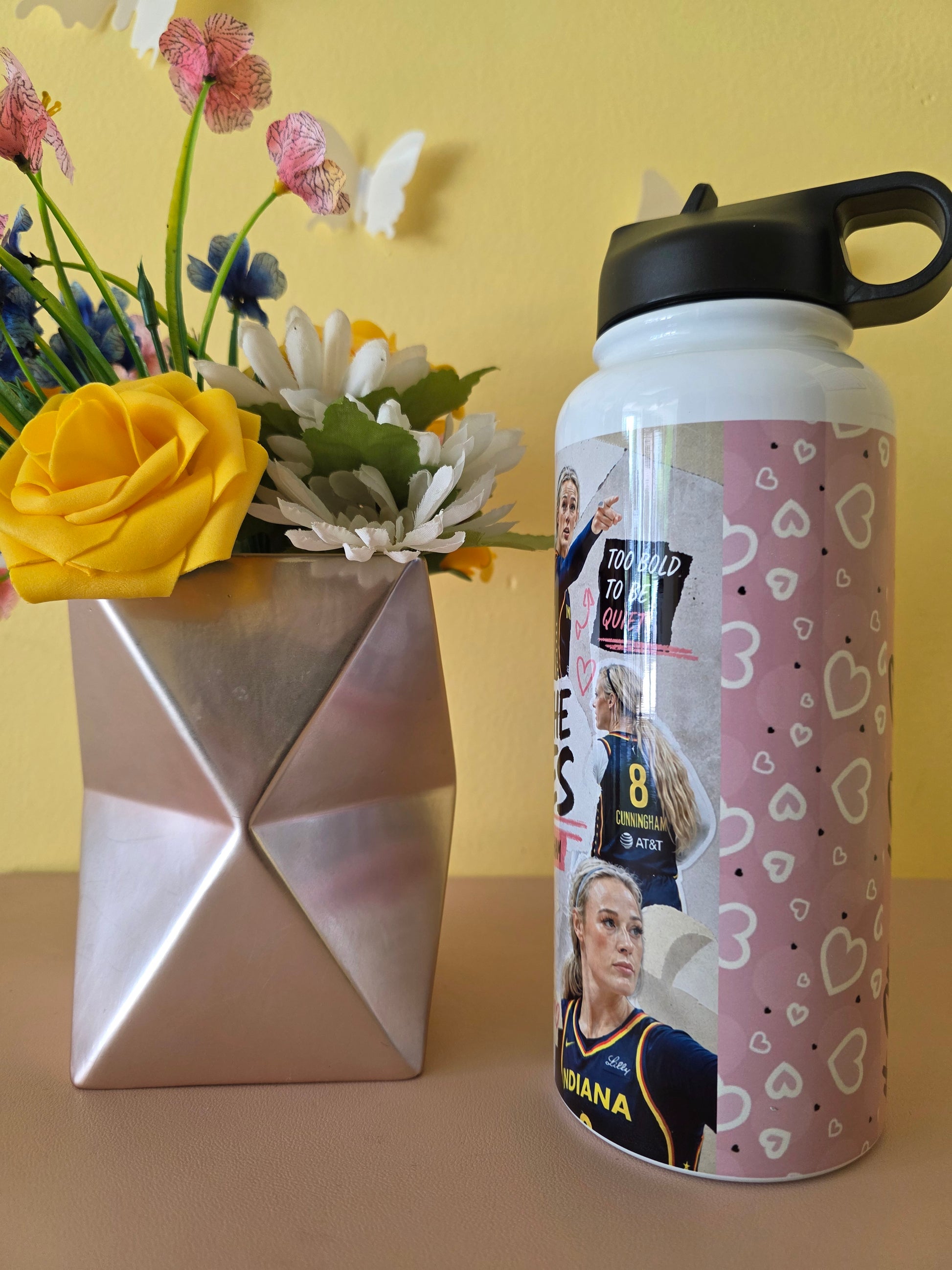 Custom women’s basketball collage water bottle with inspirational quotes displayed beside a geometric vase and yellow rose