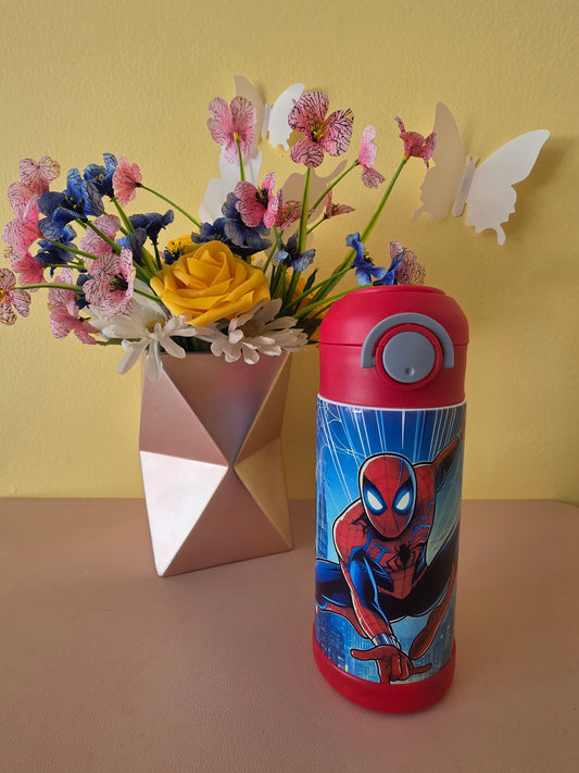 Spider-Man Superhero stainless steel water bottle for kids on a table with flowers in the background. 