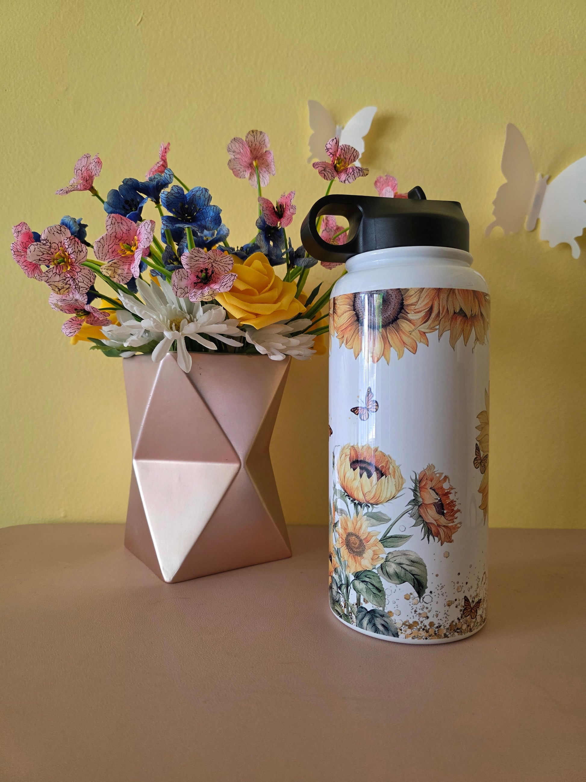 Sunflower themed water bottle tumbler on a table with yellow background